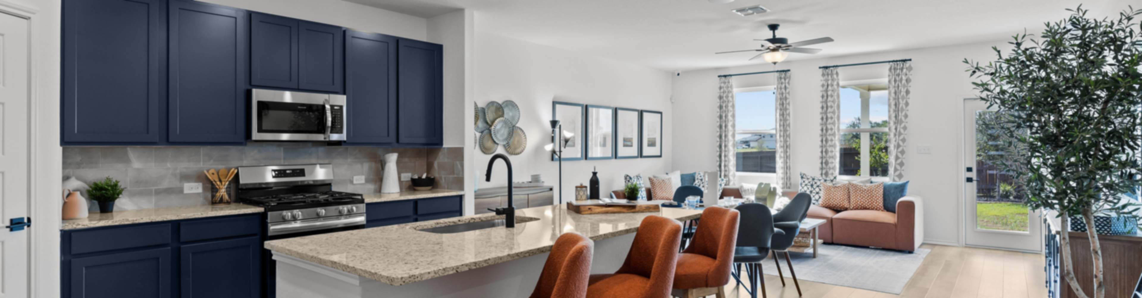 Modern open-concept kitchen and living area in new Elmendorf home with navy cabinets, granite island, orange stools