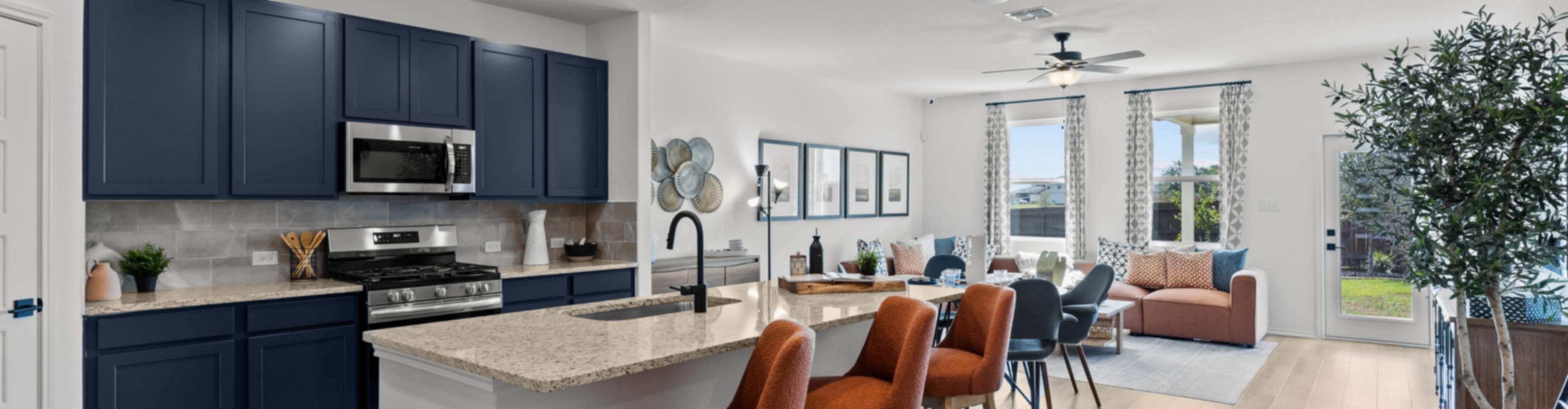 Modern open-concept kitchen and living area in new Elmendorf home with navy cabinets, granite island, orange stools
