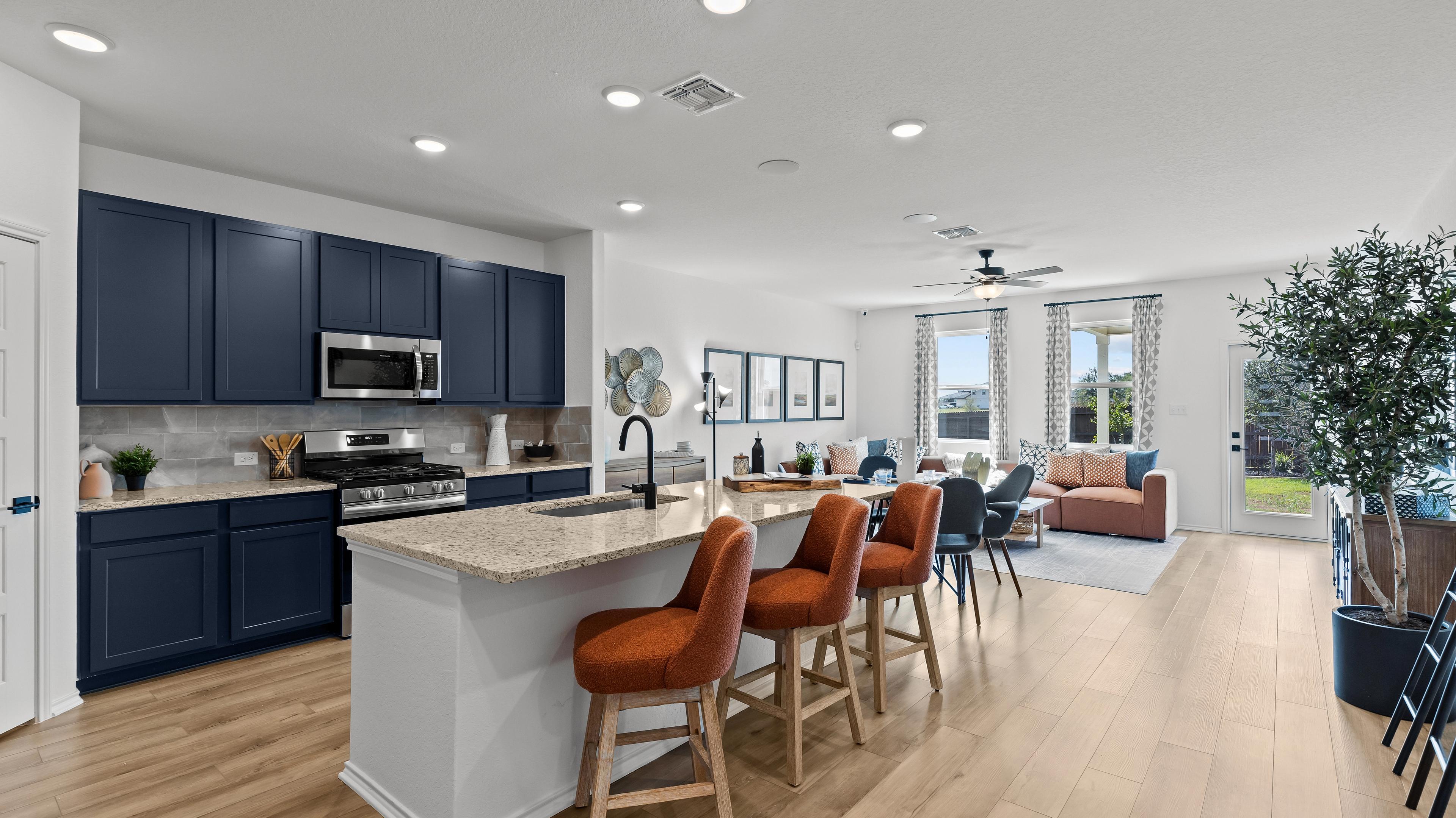 Open-concept kitchen living area at Hickory Ridge in Elmendorf Texas with navy cabinets quartz island and orange seating