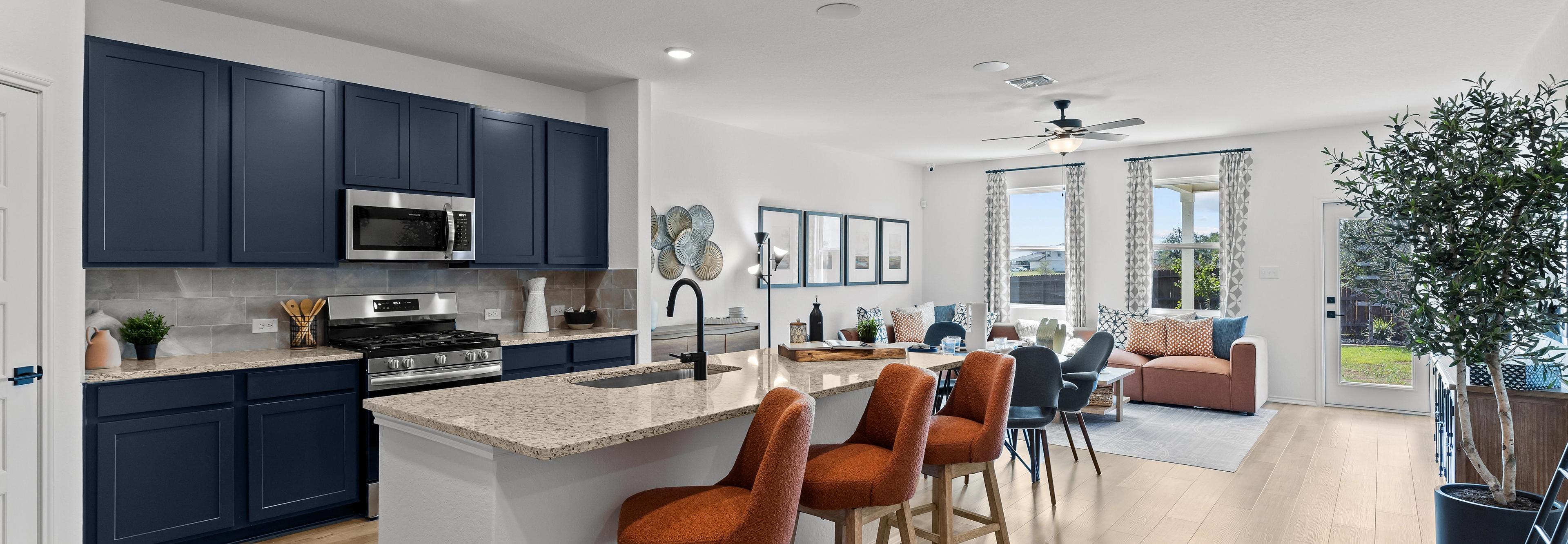 Open-concept kitchen living area at Hickory Ridge in Elmendorf Texas with navy cabinets quartz island and orange seating