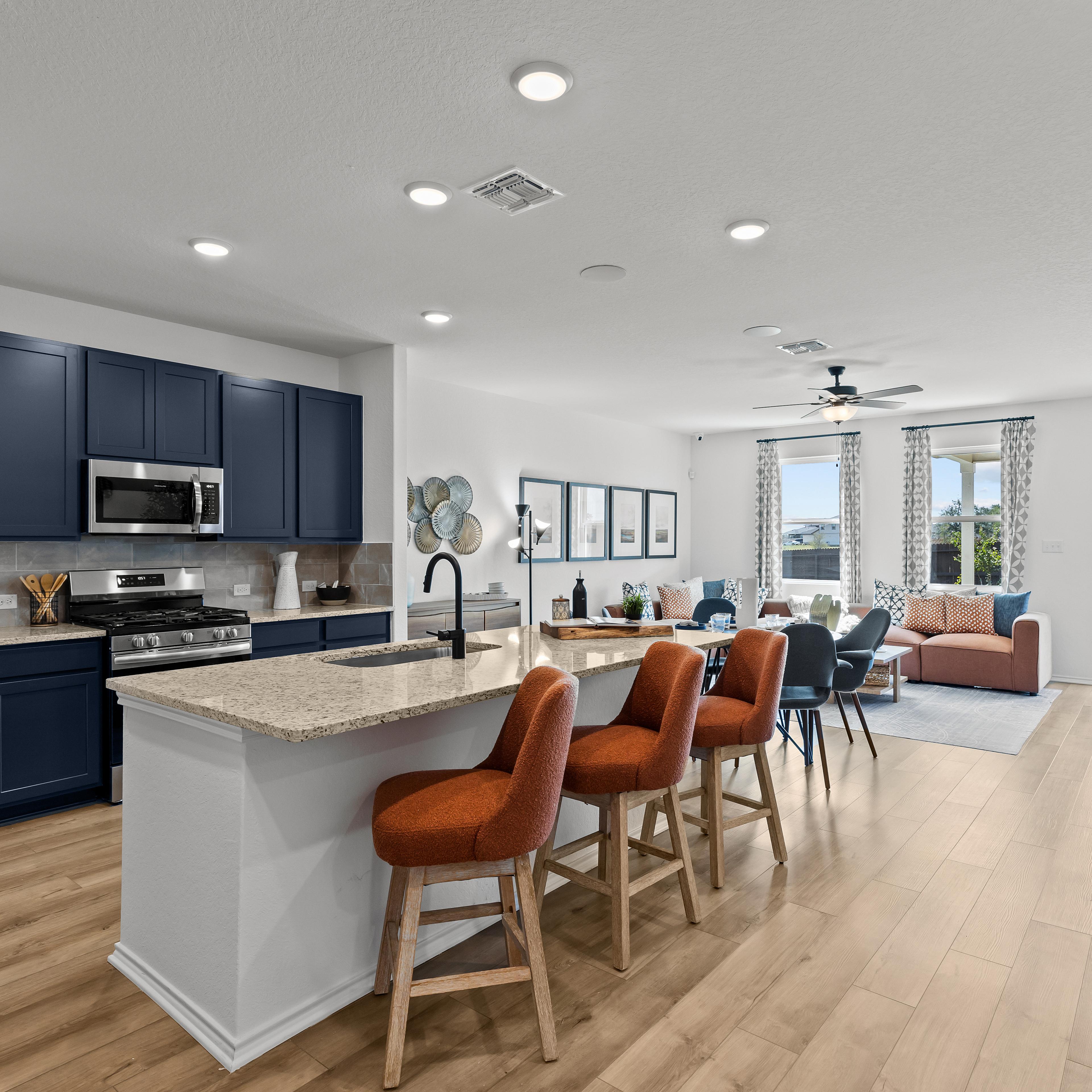 Open-concept kitchen living area at Hickory Ridge in Elmendorf Texas with navy cabinets quartz island and orange seating