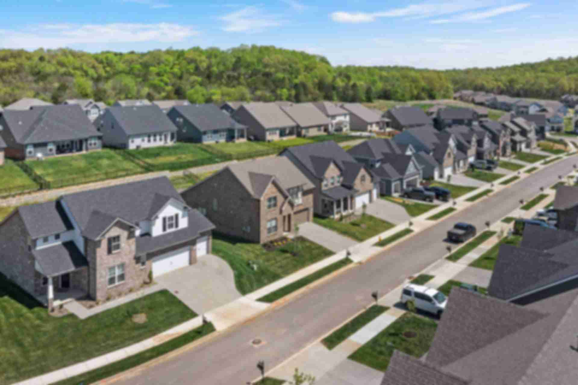 Aerial view of modern brick homes lining streets in Carellton, Gallatin Tennessee by Davidson Homes with lush green lawns