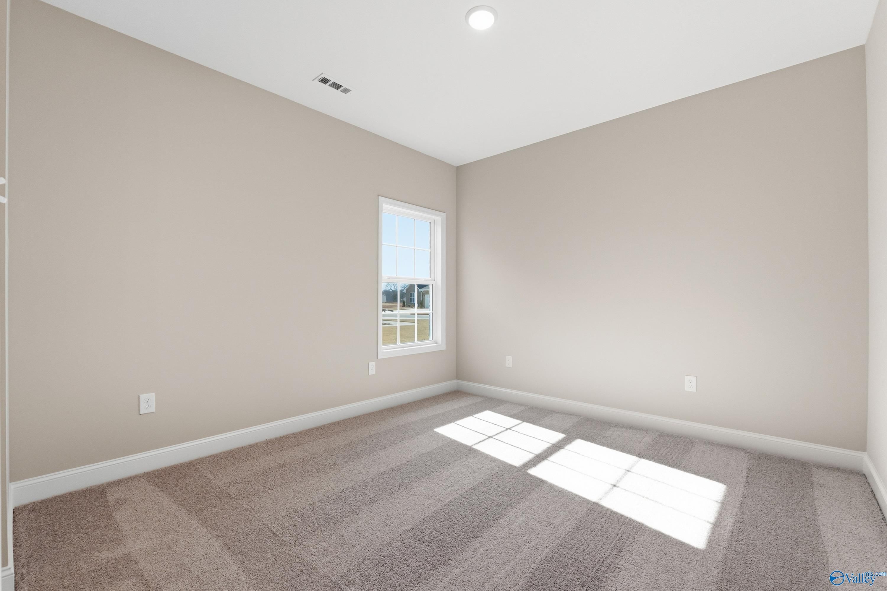 Bright secondary bedroom with beige walls, sunny window and carpeted floor in Davidson Homes The Finleigh, Meridianville, Alabama