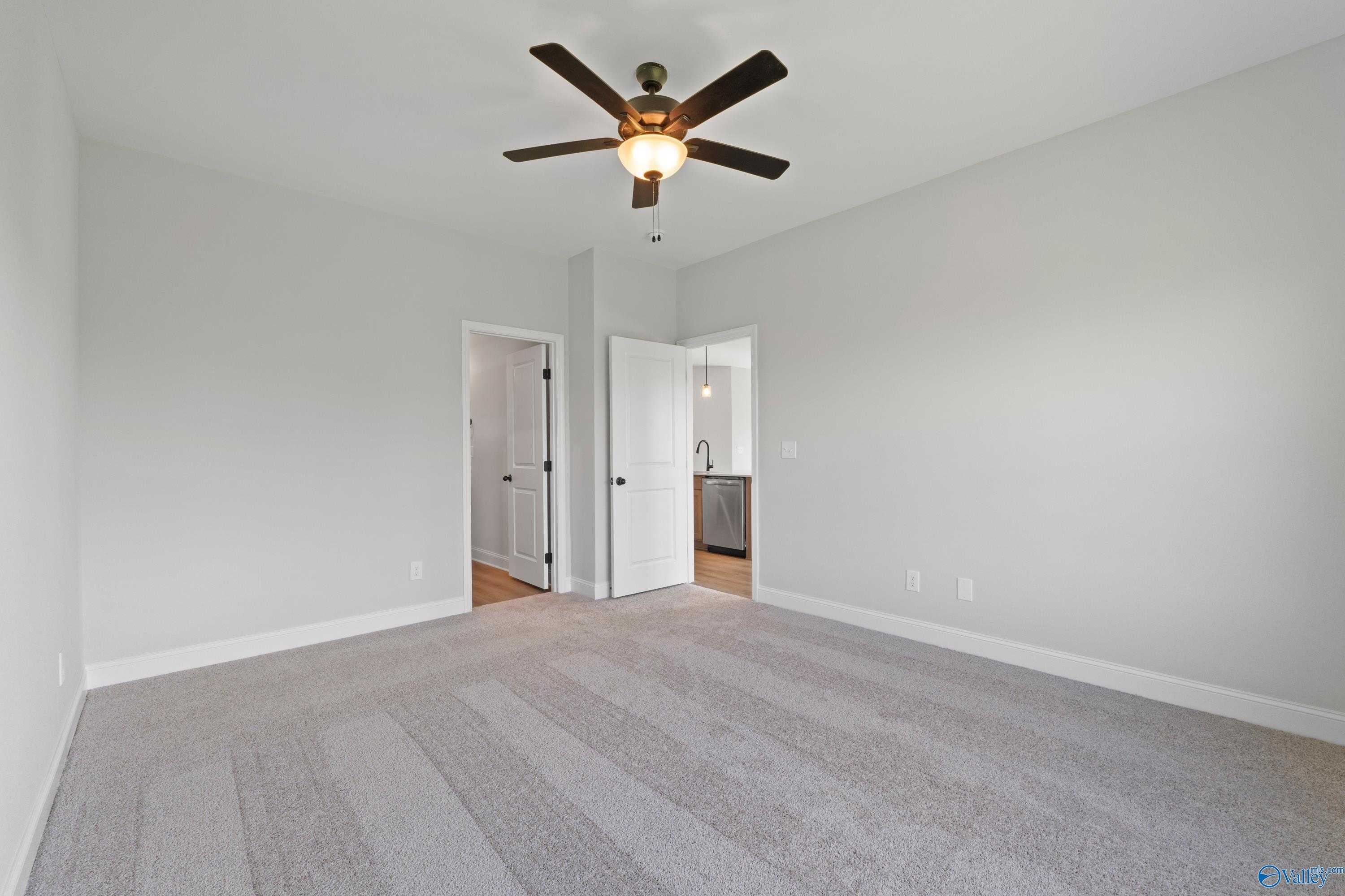 Spacious bedroom featuring ceiling fan, en-suite bathroom, and closet door in Davidson Homes The Franklin C, Hazel Green, Alabama