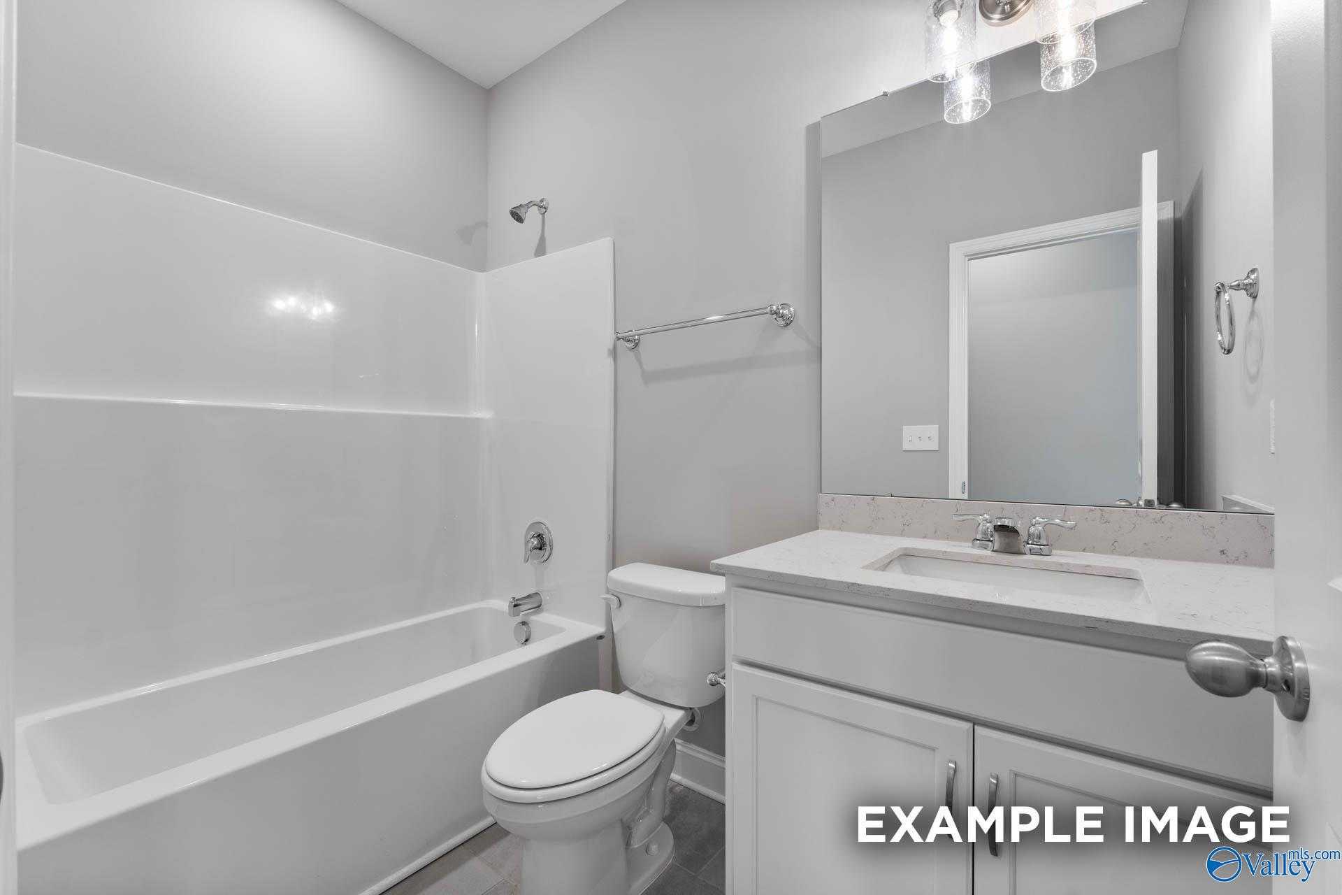 Bright guest bathroom with white tub-shower combo, vanity sink, toilet in Davidson Homes The Rockford D, Hazel Green, Alabama