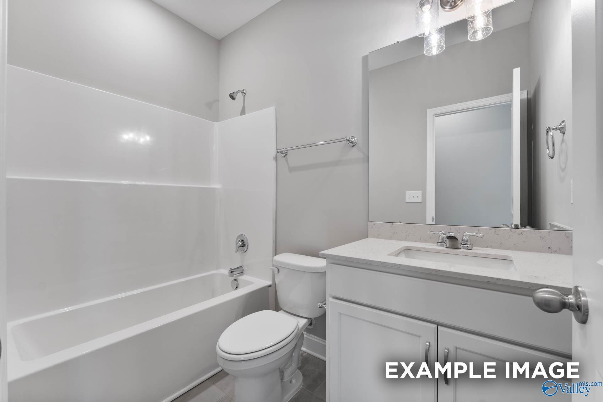 Bright bathroom with white subway tile tub-shower combo, single vanity sink, and toilet in Davidson Homes The Rockford, Madison, Alabama