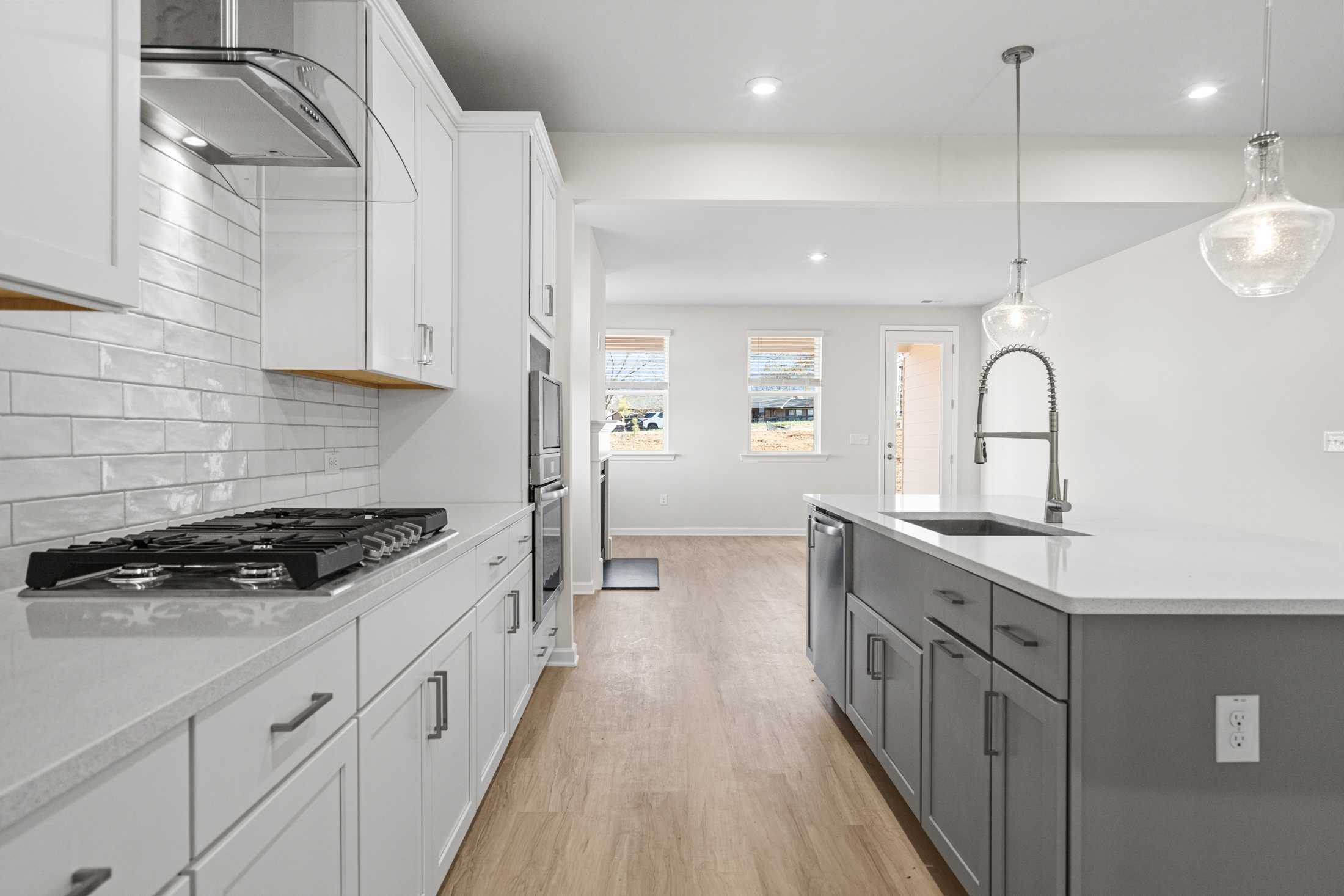 Spacious kitchen in The Glenwood A with white shaker cabinets, quartz island, subway tile backsplash, and open dining area