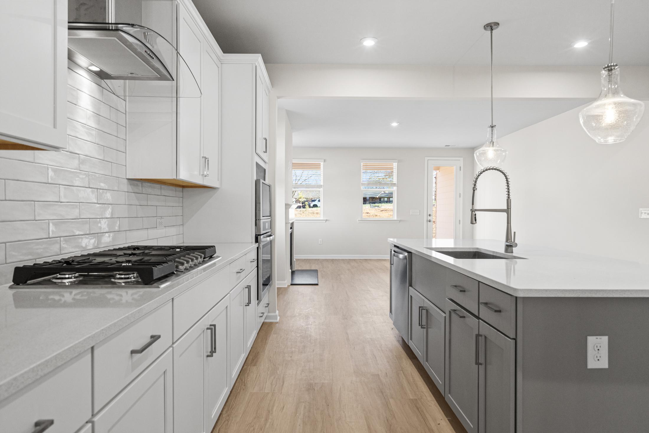 Spacious kitchen in The Glenwood A with white shaker cabinets, quartz island, subway tile backsplash, and open dining area
