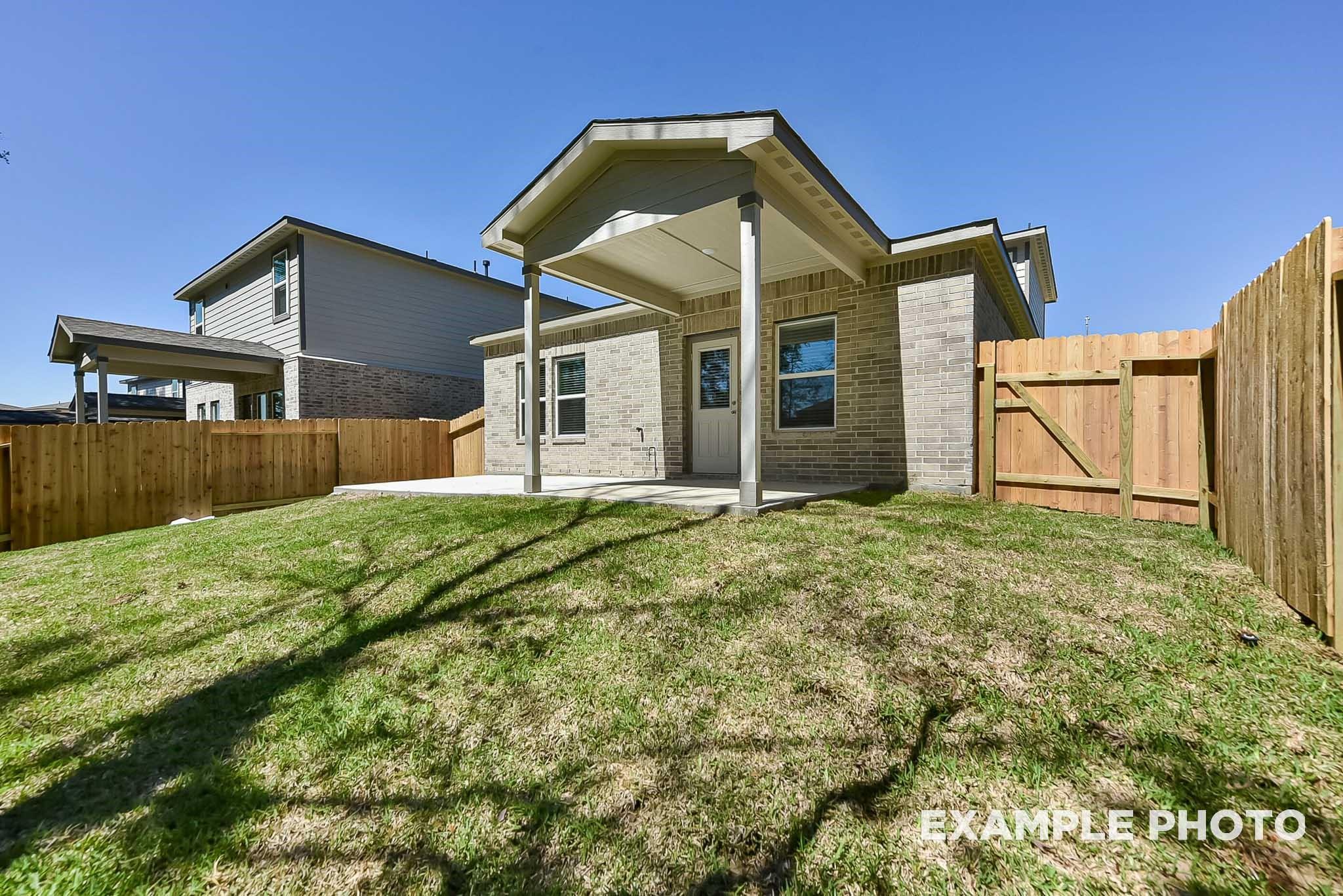 Covered back patio and private fenced backyard of The Blanco E floor plan home in Caney Creek Place, Conroe, Texas.
