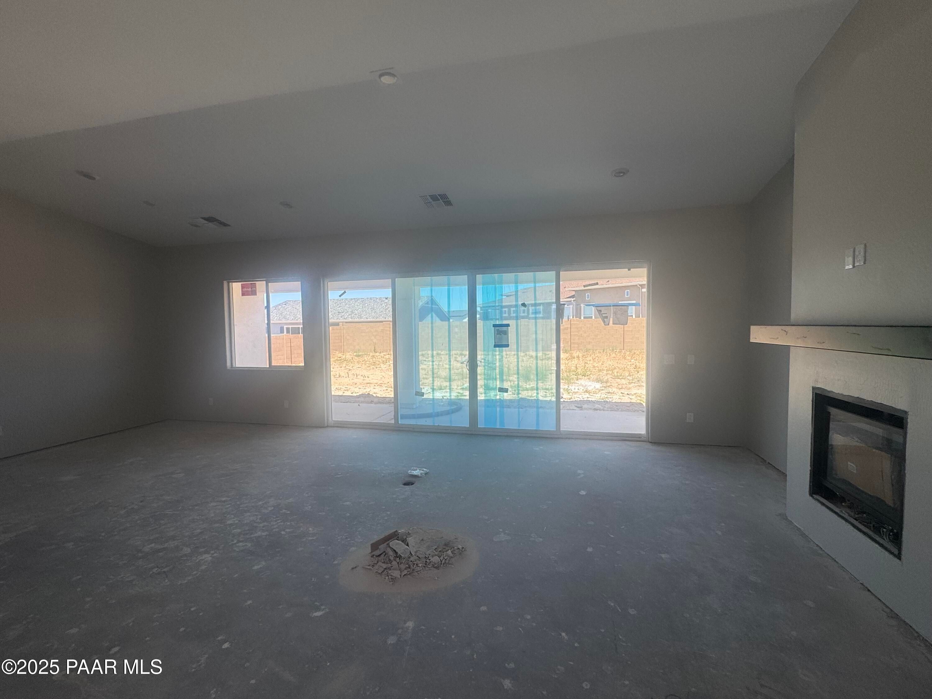 Spacious empty great room with fireplace, sliding glass doors to desert backyard, vaulted ceiling in Davidson Homes The Daybreak E, Prescott AZ