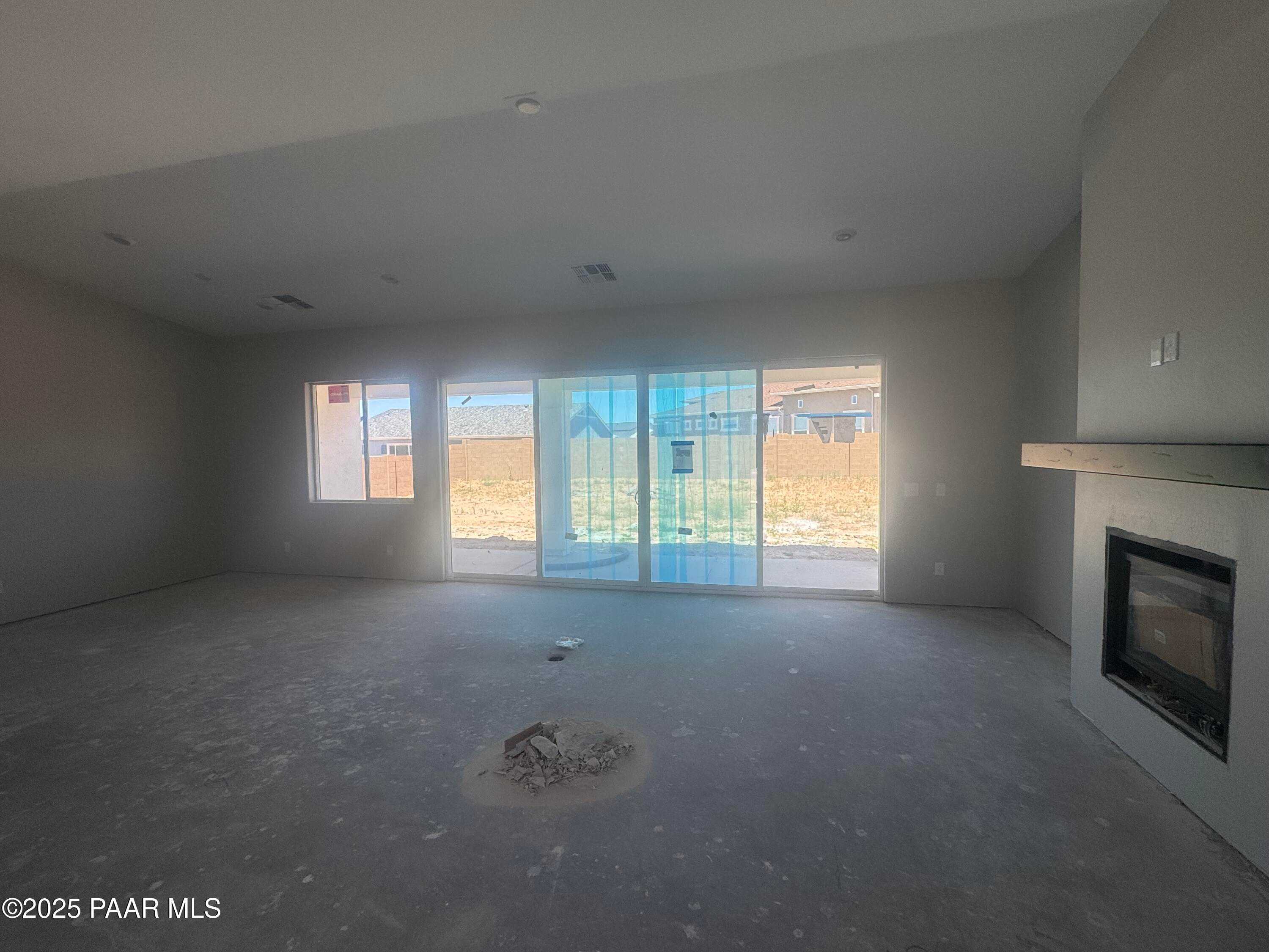 Spacious empty great room with fireplace, sliding glass doors to desert backyard, vaulted ceiling in Davidson Homes The Daybreak E, Prescott AZ