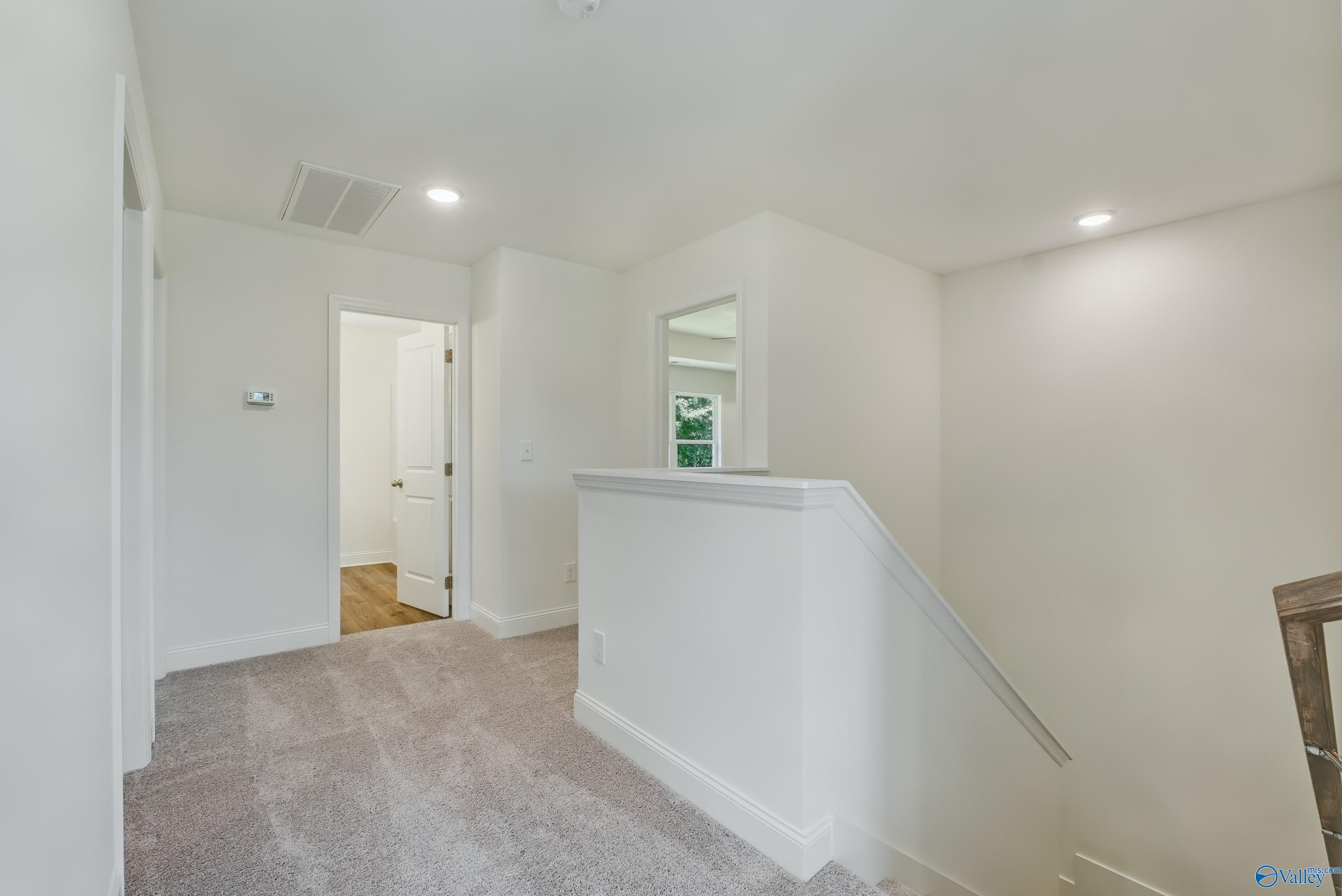 Bright upstairs hallway with white walls, gray carpet, and staircase railing in The Shelby A 4-bedroom home, Arab, Alabama