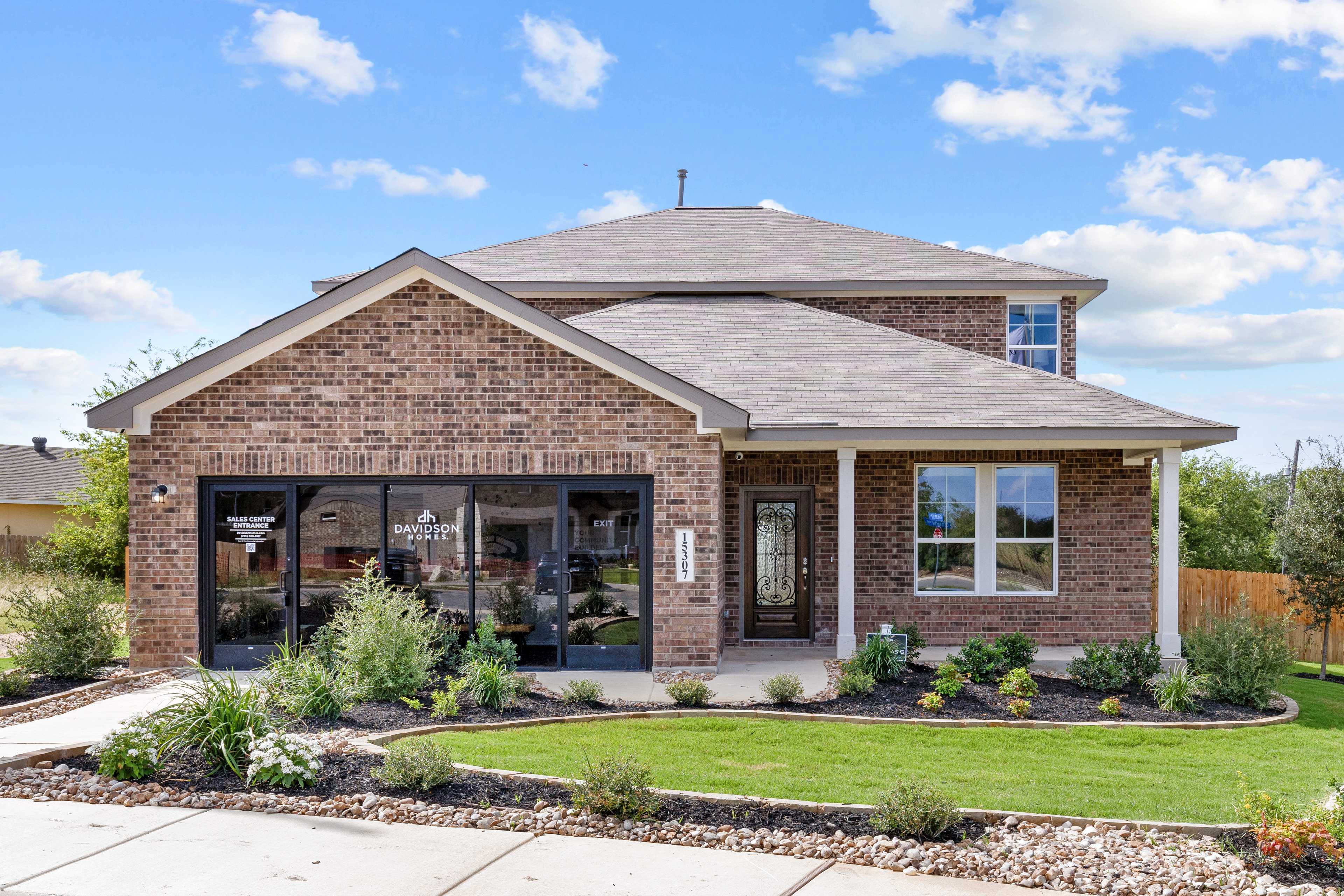Two-story brick home exterior at Comanche Ridge in San Antonio TX with covered porch, garage, and landscaped yard