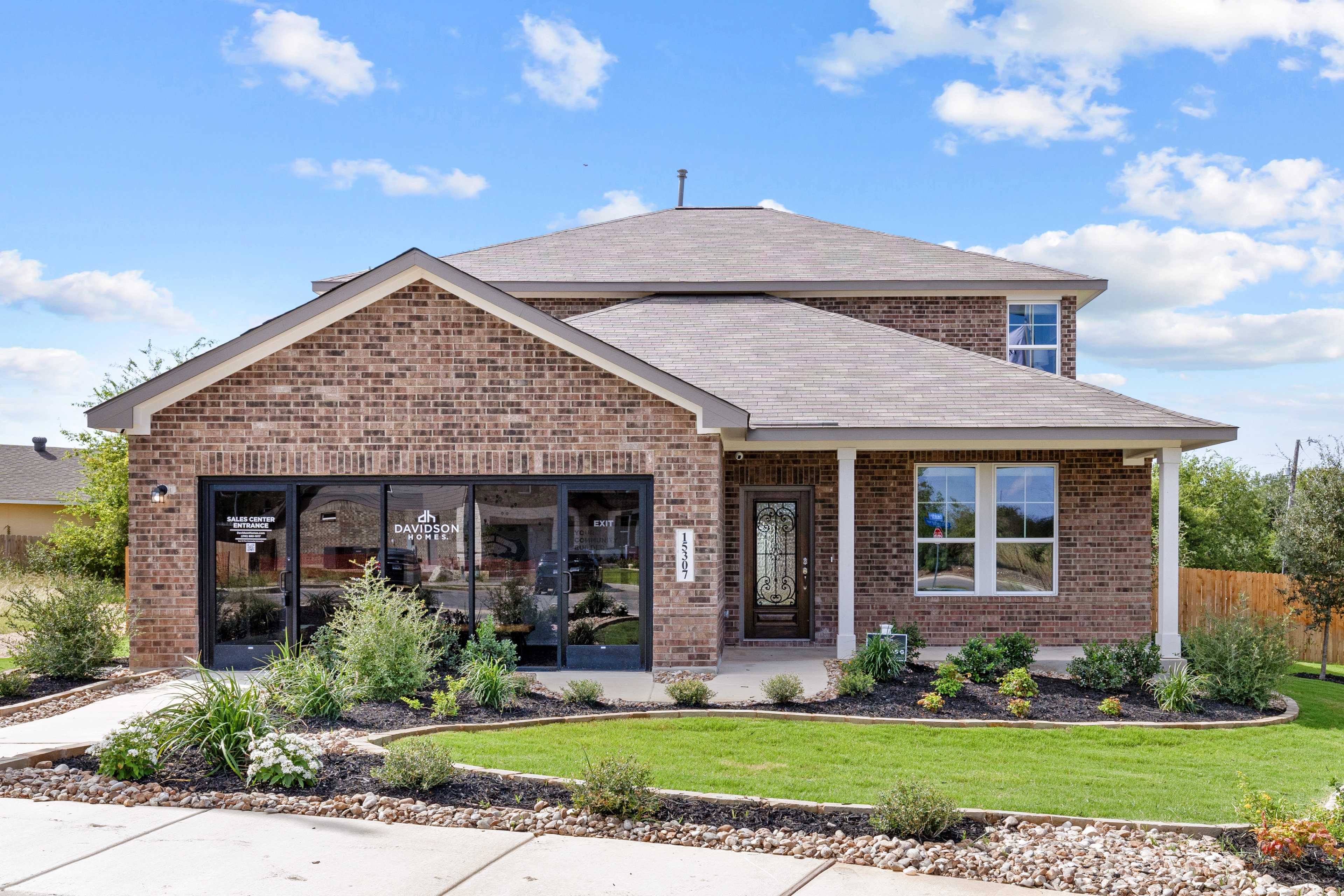 Two-story brick home exterior at Comanche Ridge in San Antonio TX with covered porch, garage, and landscaped yard