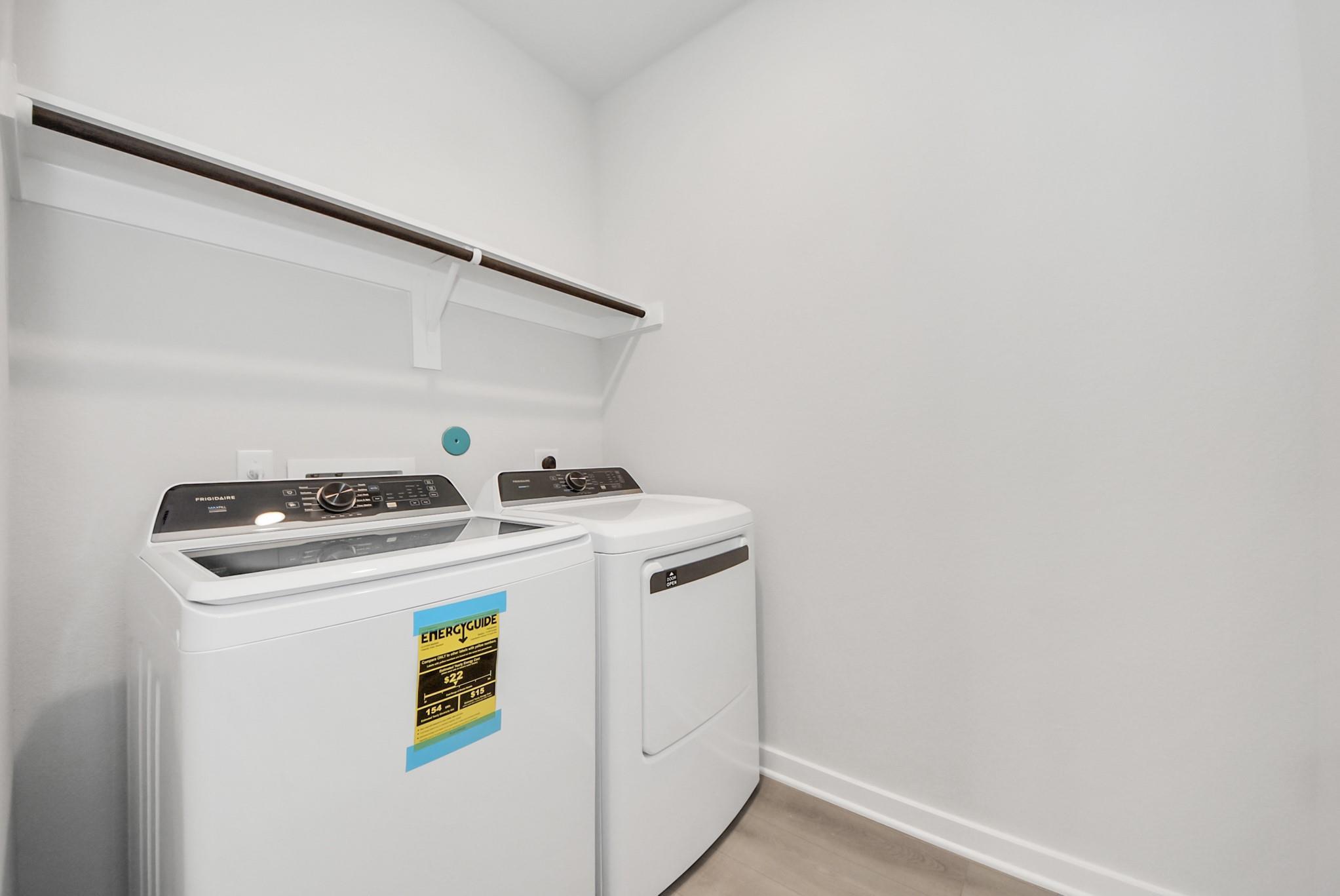 Laundry room with white washer and dryer and built-in shelving in Davidson Homes The Verano B floor plan in Sunterra, Katy.