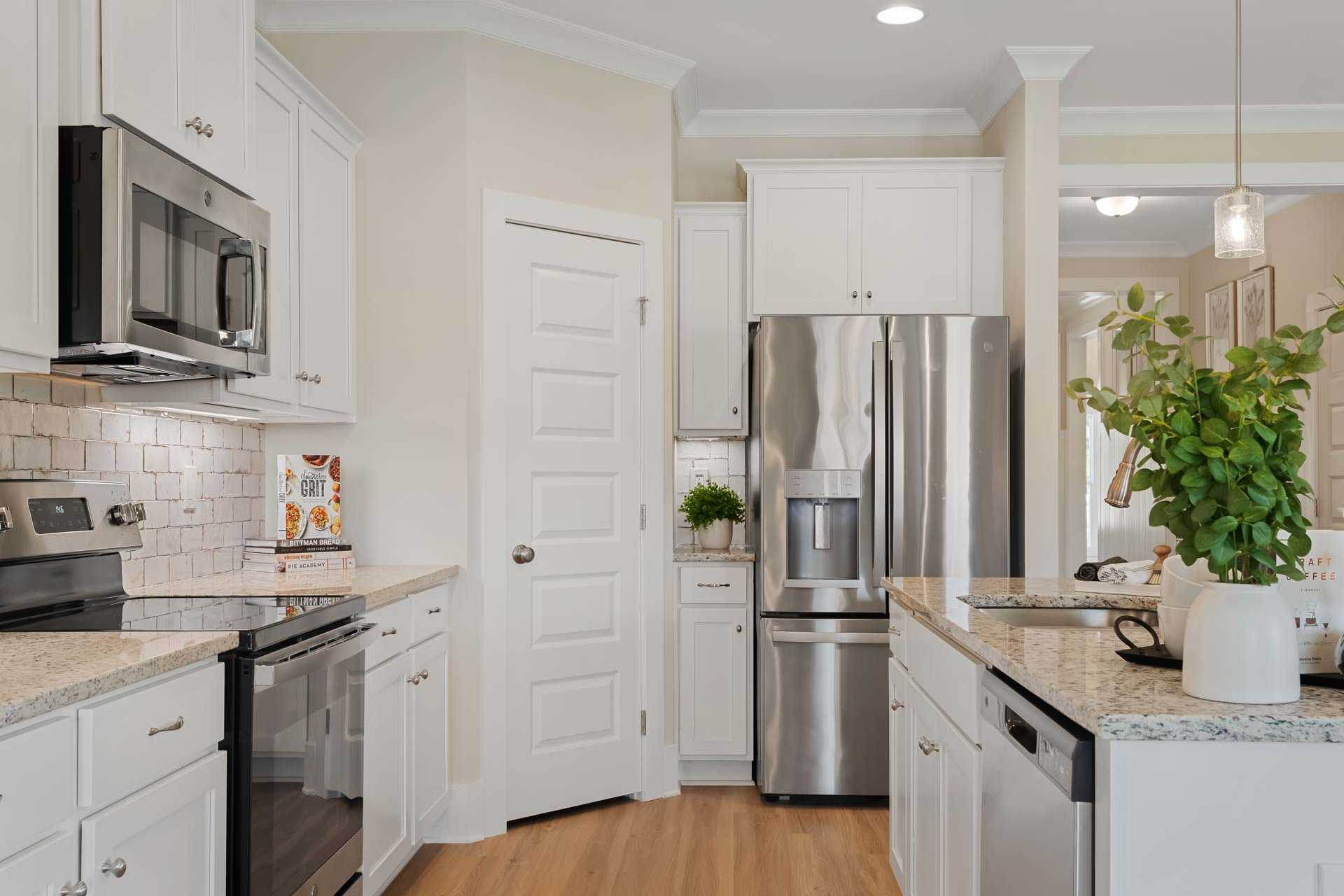 Spacious white kitchen at Flint Meadows in New Market, Alabama with stainless steel appliances, granite counters, and subway tile