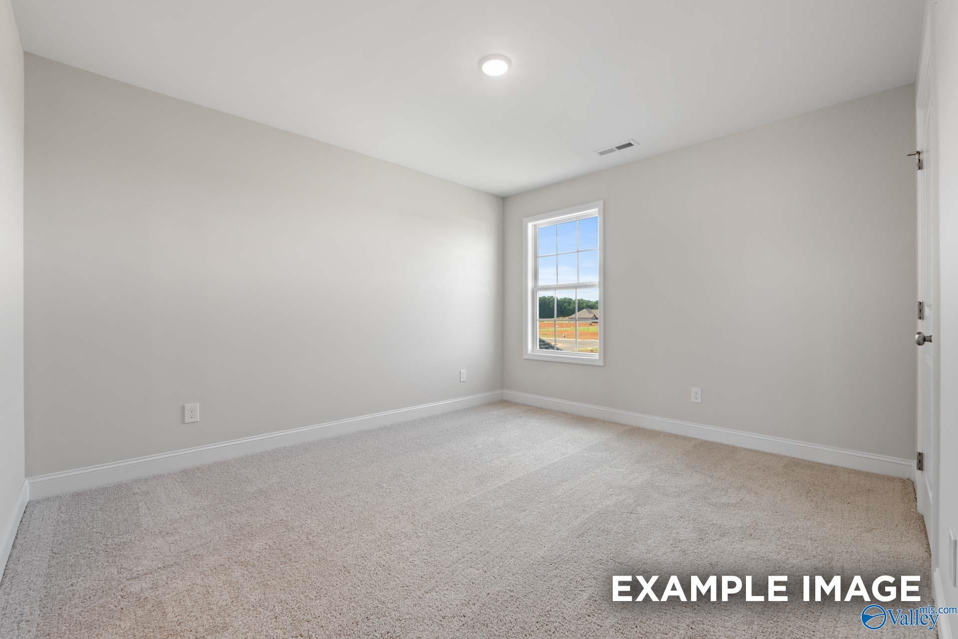 Bright empty bedroom with gray walls, beige carpet, large window, and natural light in Davidson Homes The Madison A, Toney, Alabama
