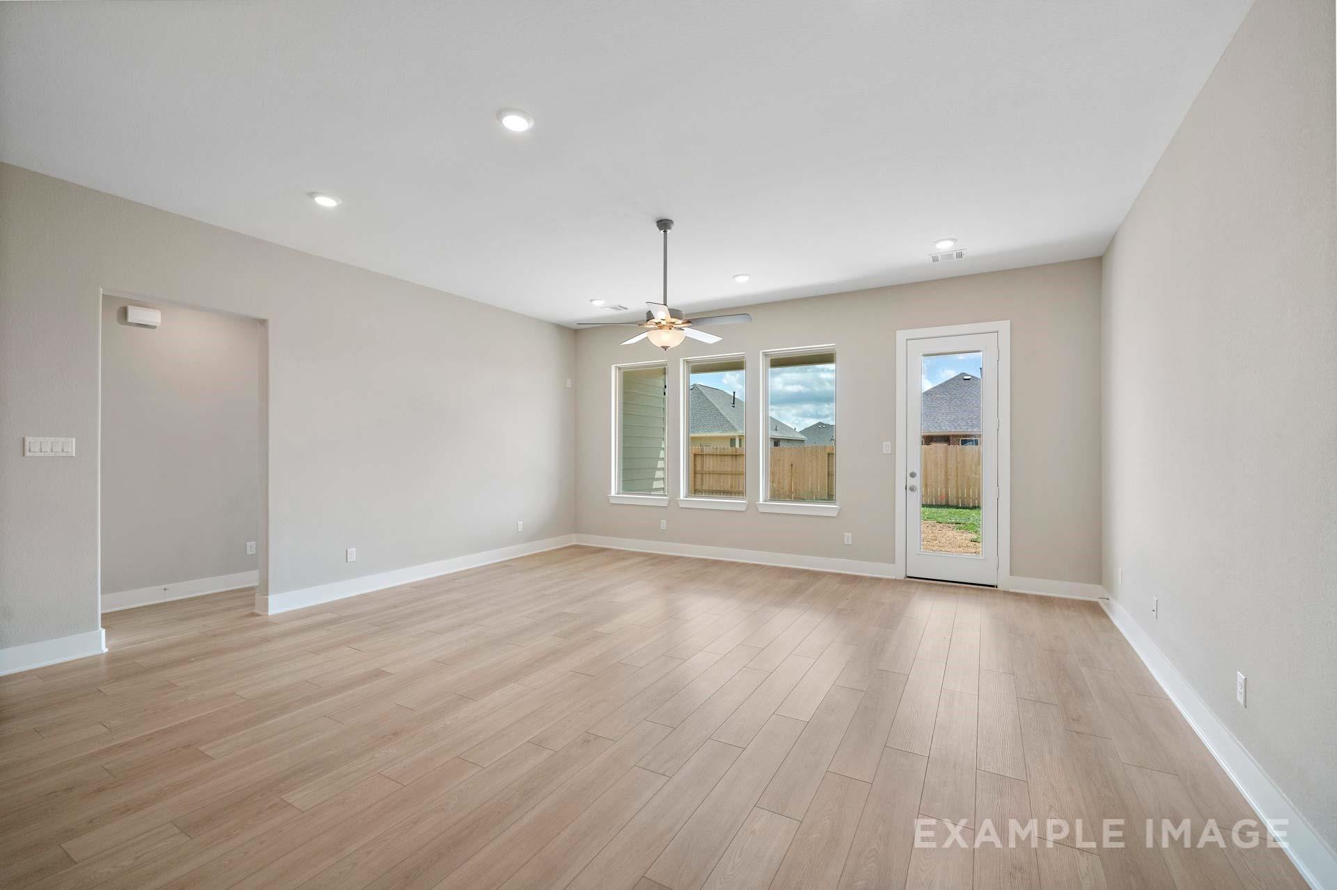 Bright open-concept living room with wood-look tile floors in Davidson Homes' The Elizabeth A, Lago Mar, Texas City