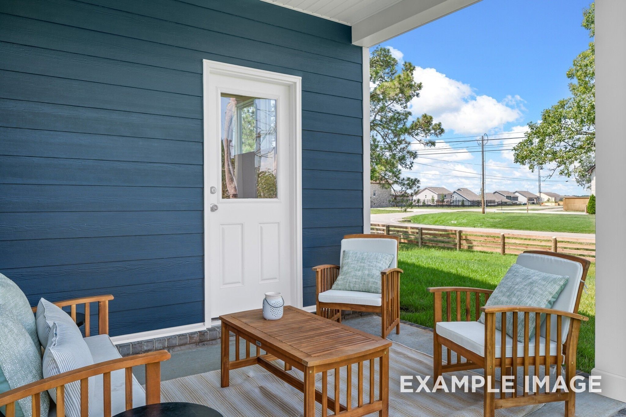 Covered back patio with wooden chairs and table overlooking green yard and trees in Davidson Homes The Ash A, Woods Crossing, Gallatin, TN