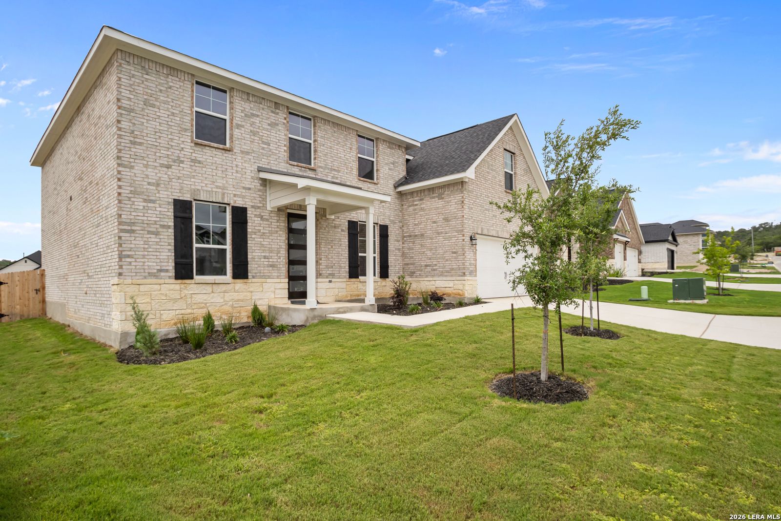 Two-story brick and stone home, The Danbury H floor plan, at The Reserve at Potranco Oaks in Castroville, Texas.