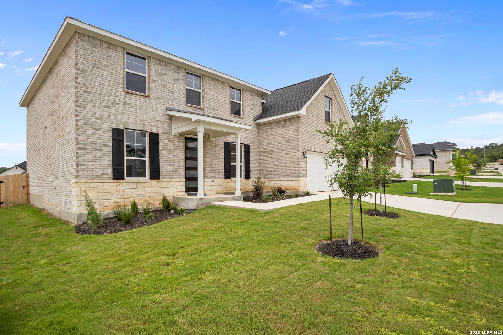 Two-story brick and stone home, The Danbury H floor plan, at The Reserve at Potranco Oaks in Castroville, Texas.