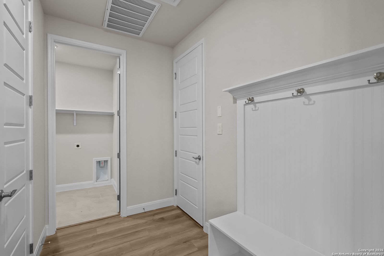 Functional mudroom-laundry with built-in bench, coat hooks, washer dryer hookups in Davidson Homes The Lanier H, Ladera San Antonio