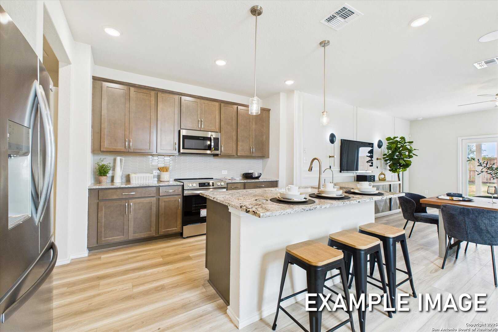 Modern open-concept kitchen featuring granite island, stainless steel appliances, and shaker cabinets in Davidson Homes The Brazos C, San Antonio