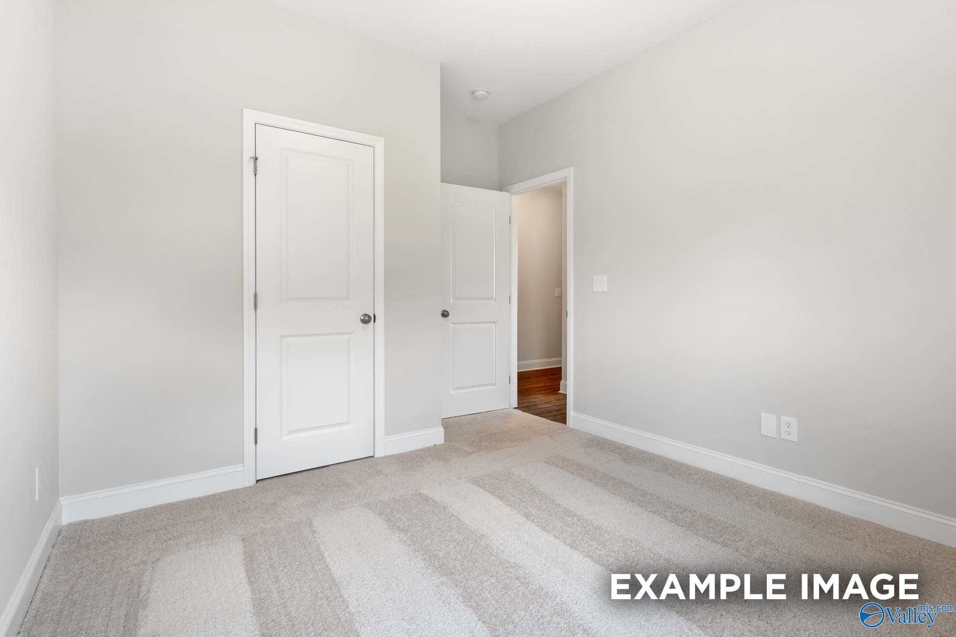 Empty secondary bedroom featuring gray walls, white doors, and beige carpet in The Asheville C, Davidson Homes, Meridianville, AL