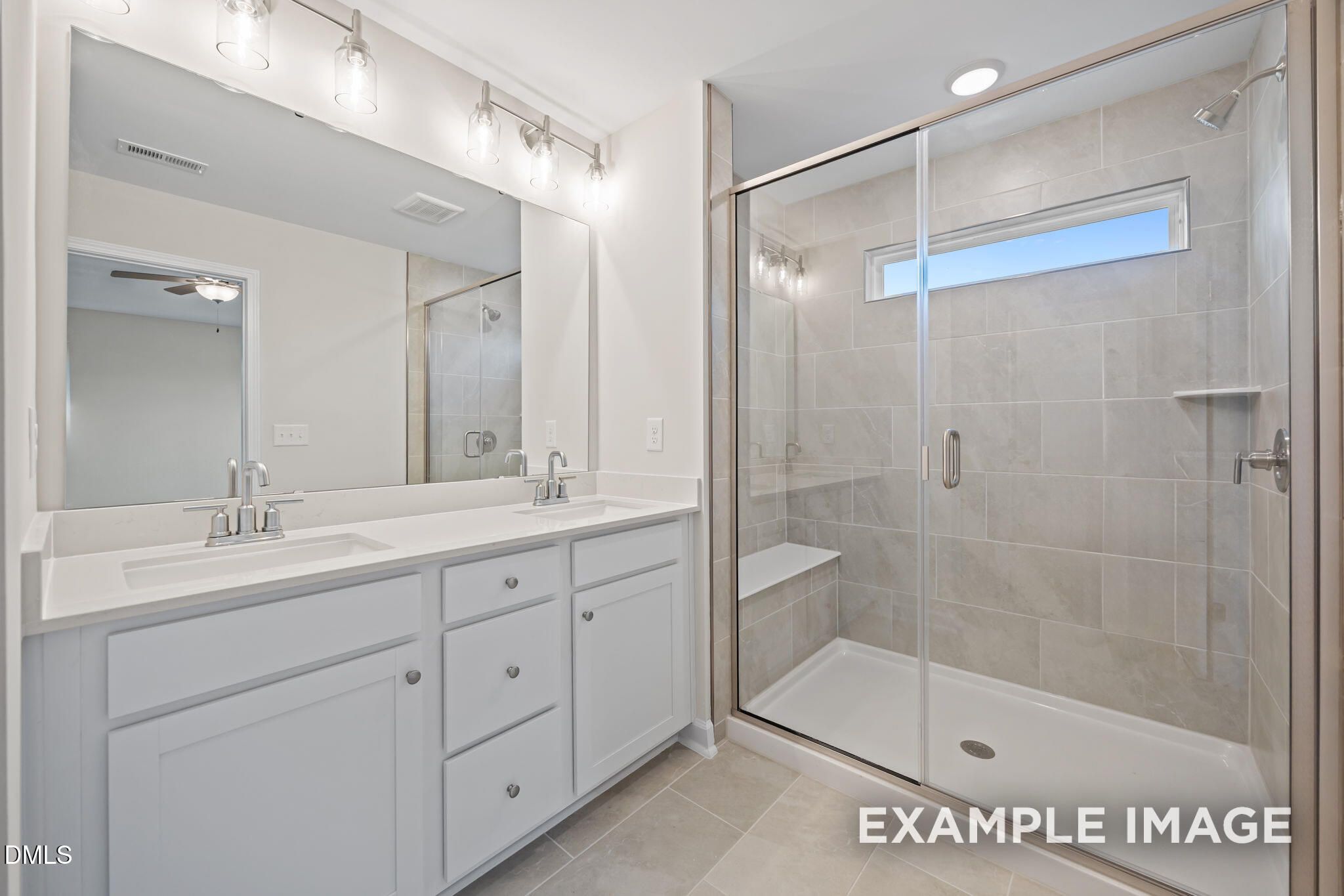 Modern master bathroom featuring double vanity with white cabinets and frameless glass shower in Davidson Homes The Avery, Knightdale, NC