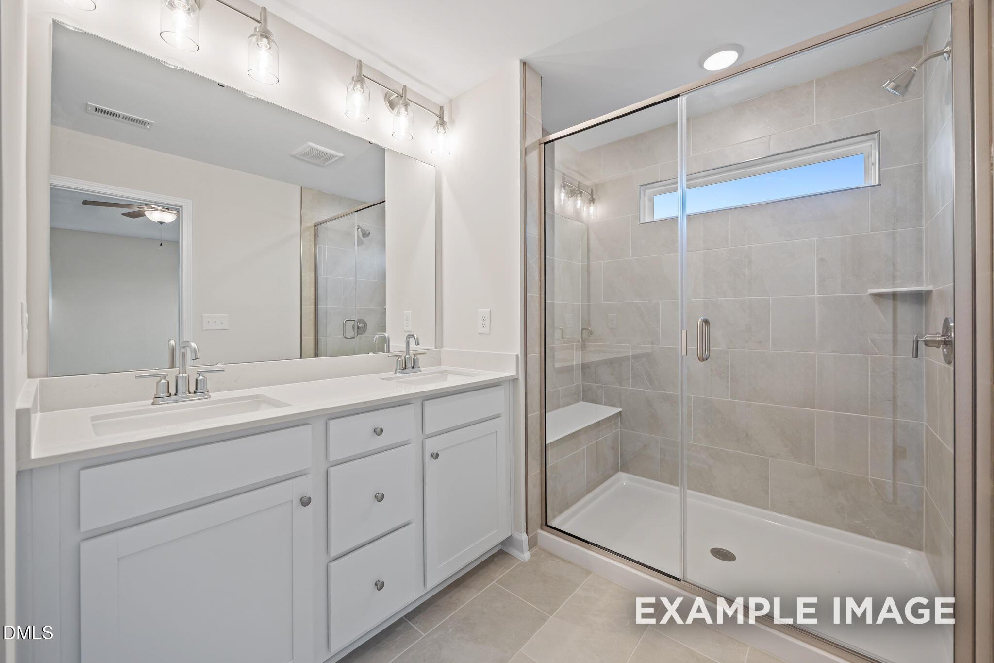 Modern master bathroom featuring double vanity with white cabinets and frameless glass shower in Davidson Homes The Avery, Knightdale, NC