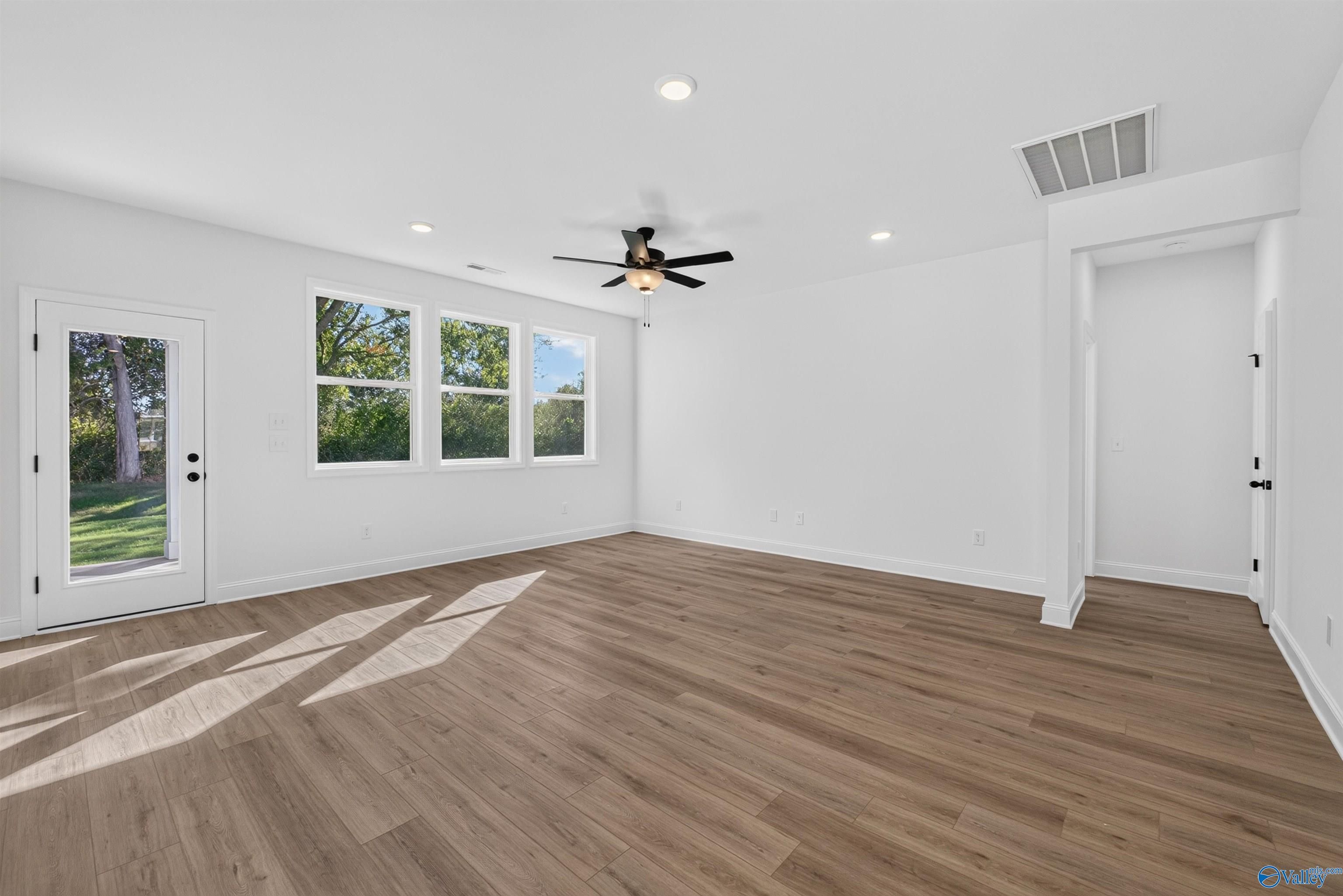 Bright sunlit room with luxury vinyl plank flooring, ceiling fan, and backyard views in Davidson Homes Ashport L, Berry Cove.