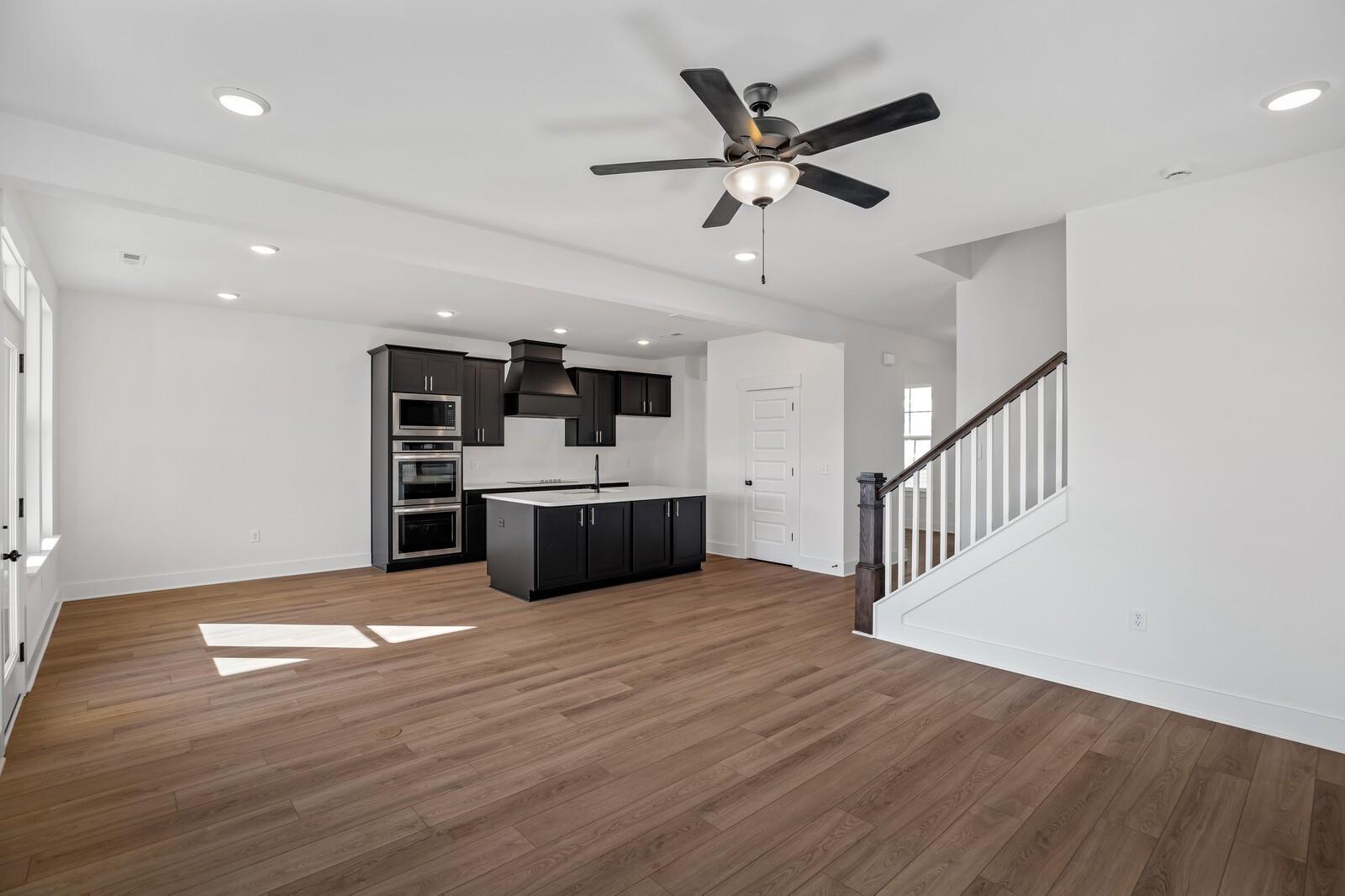 Modern open kitchen with black cabinets, large island, stainless appliances, and hardwood floors in The Willow C, Gallatin, TN