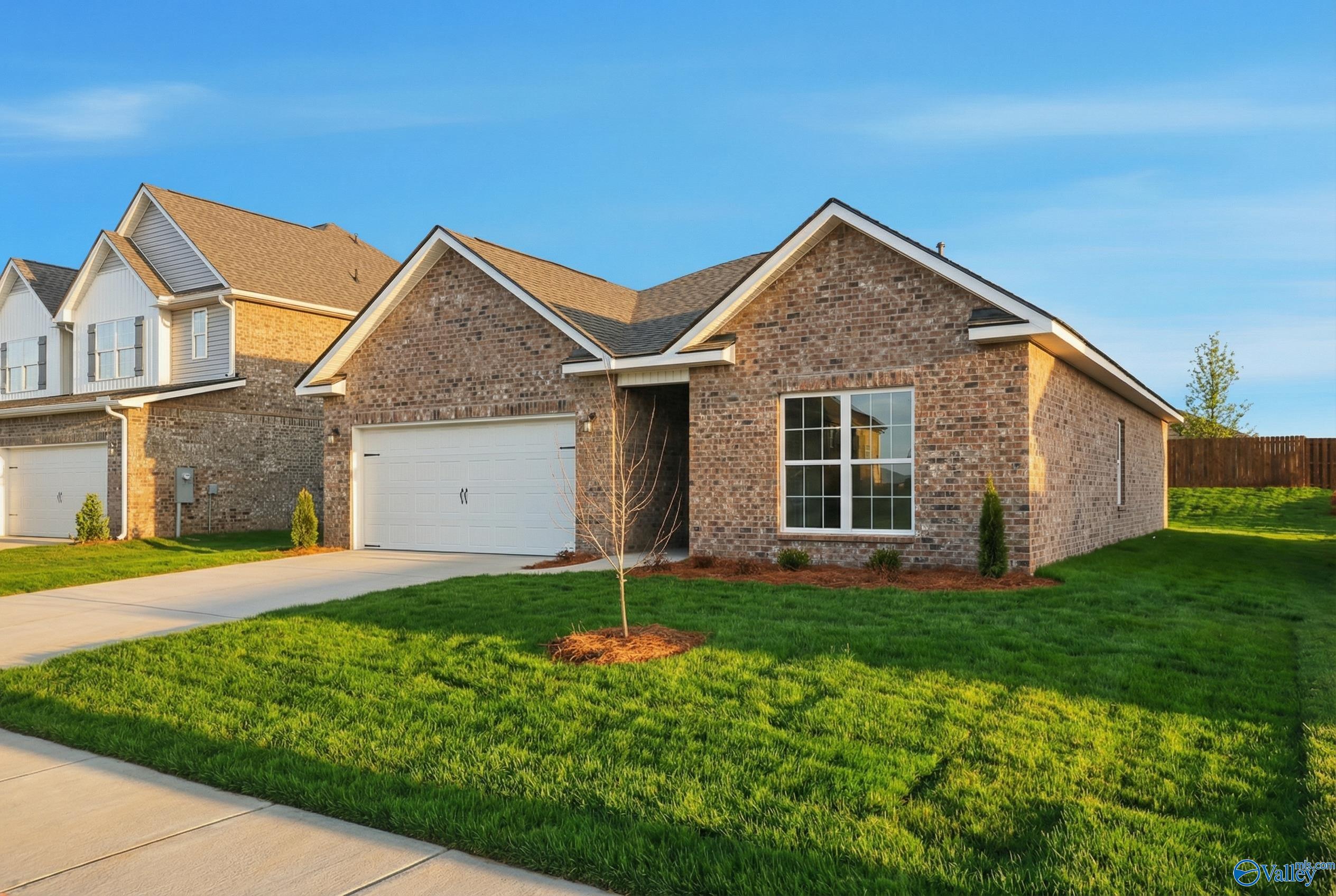 Modern brick ranch home with 2-car garage, gabled roof, large window, driveway, and lush green lawn in Walker's Hill, Meridianville, Alabama