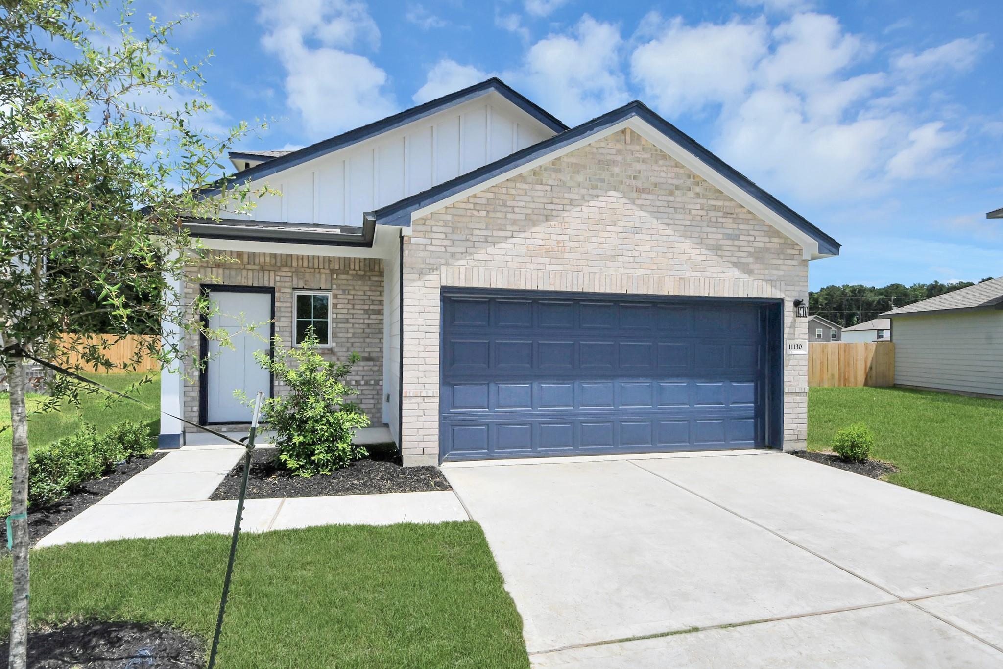 Brick and white siding exterior of The Sabine F floor plan with a 2-car garage in Liberty Estates, Cleveland, Texas.