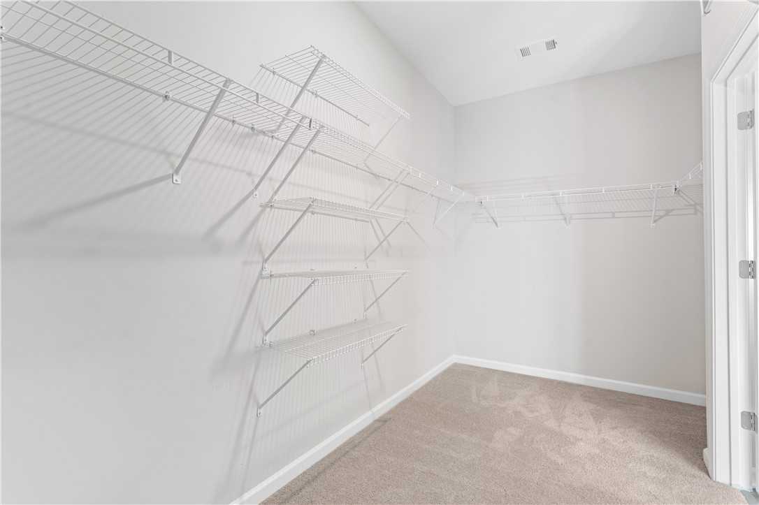 Spacious walk-in closet with white wire shelving and beige carpet flooring in Davidson Homes The Luna B, Opelika, Alabama