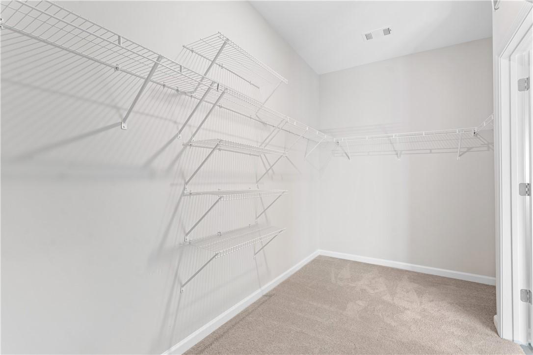 Spacious walk-in closet with white wire shelving and beige carpet flooring in Davidson Homes The Luna B, Opelika, Alabama