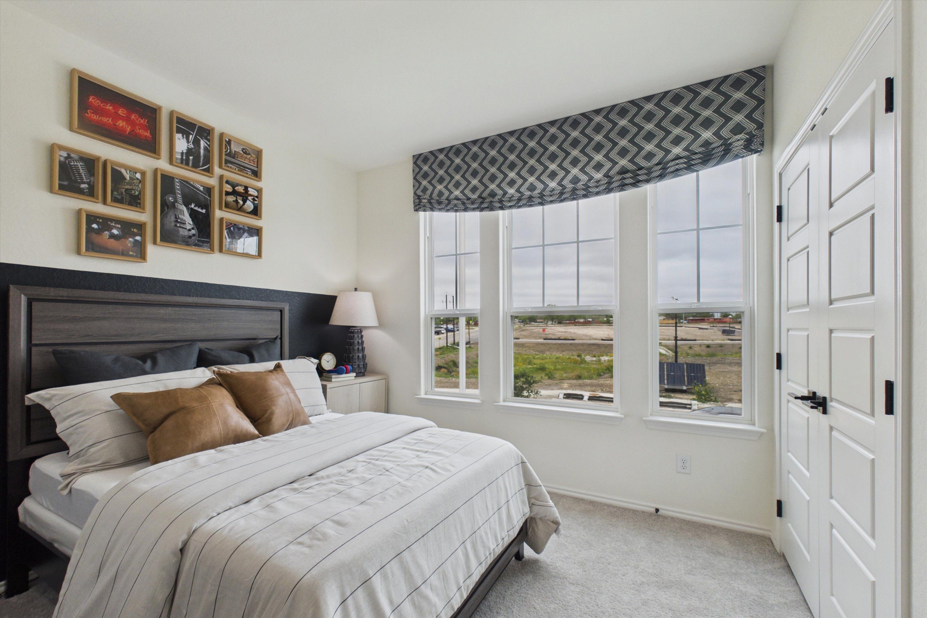 Cozy master bedroom in Rayburn Valley San Antonio with king bed, panoramic windows overlooking landscape, and rock music wall art