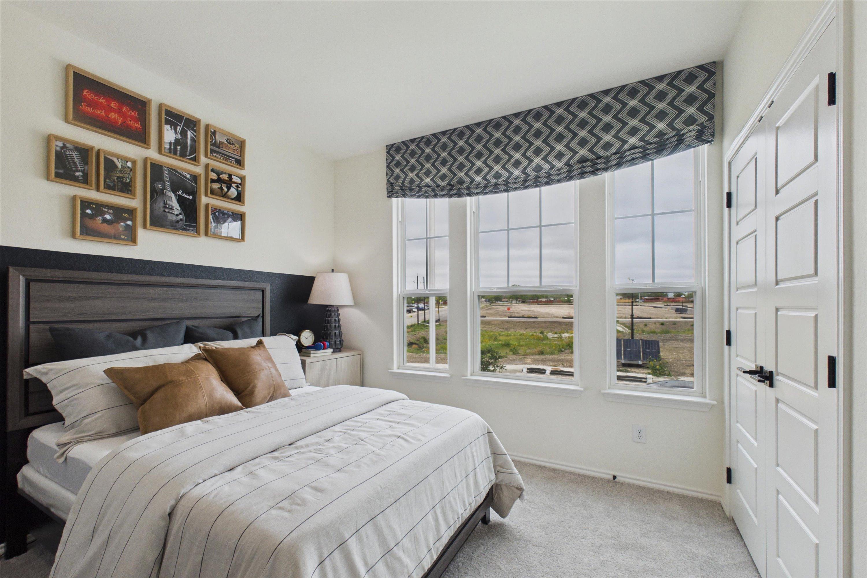 Cozy master bedroom in Rayburn Valley San Antonio with king bed, panoramic windows overlooking landscape, and rock music wall art
