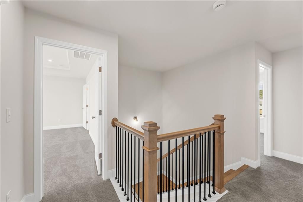 Elegant oak staircase with wrought iron balusters in upper hallway of Davidson Homes The Willow B, Hoschton, GA