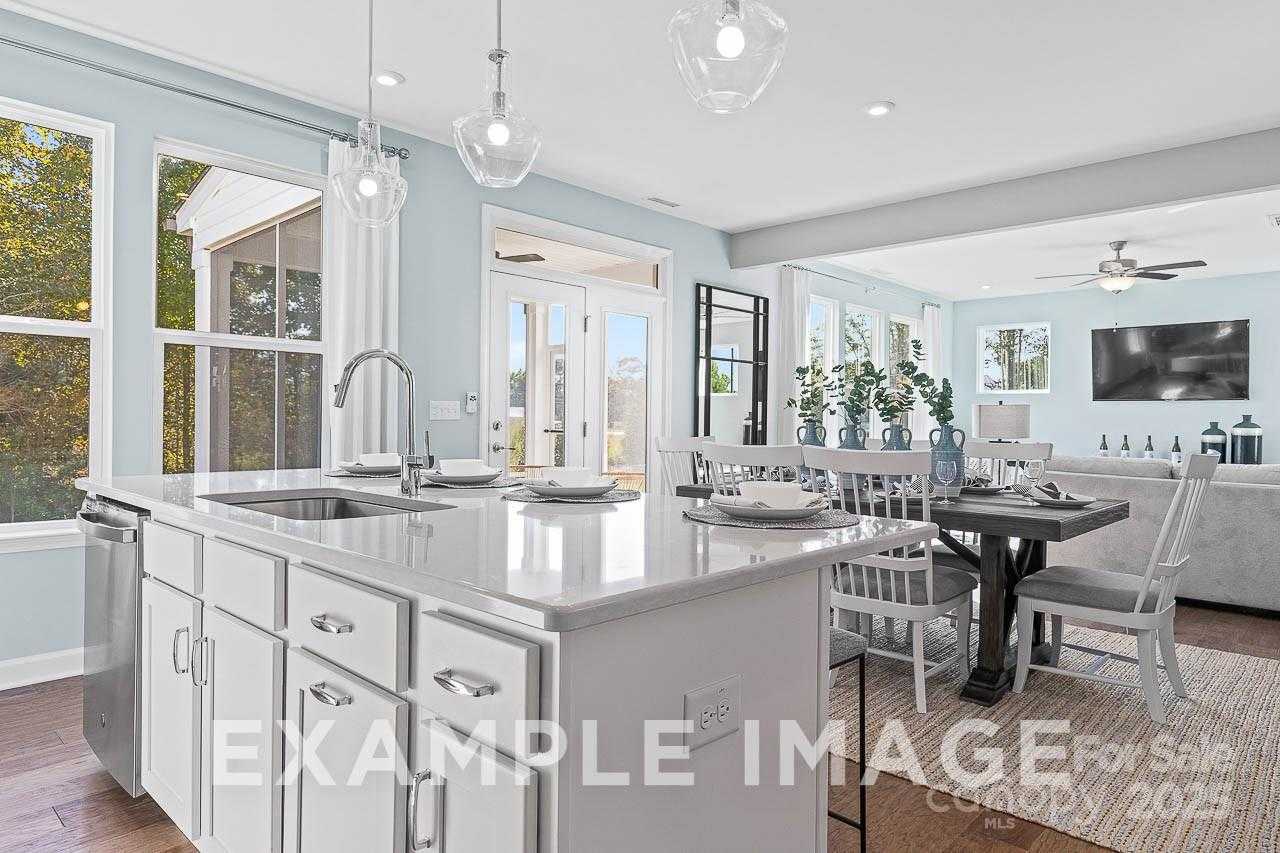 Bright open-concept kitchen with white shaker cabinets, quartz island, farmhouse sink, and dining table in The Hemlock A, Belmont, NC