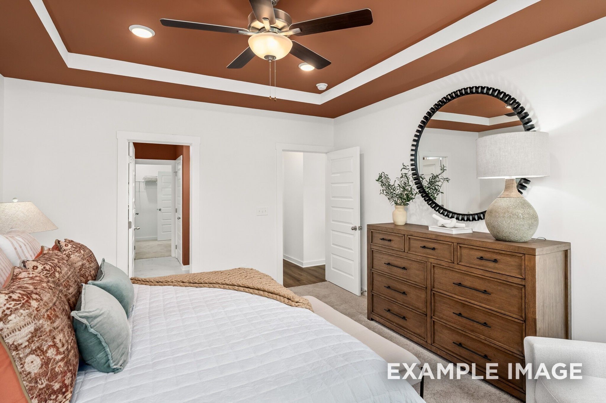 Elegant master bedroom with ceiling fan, plush white bedding, wooden dresser, and en-suite bath door in Davidson Homes The Ash A, Gallatin, TN