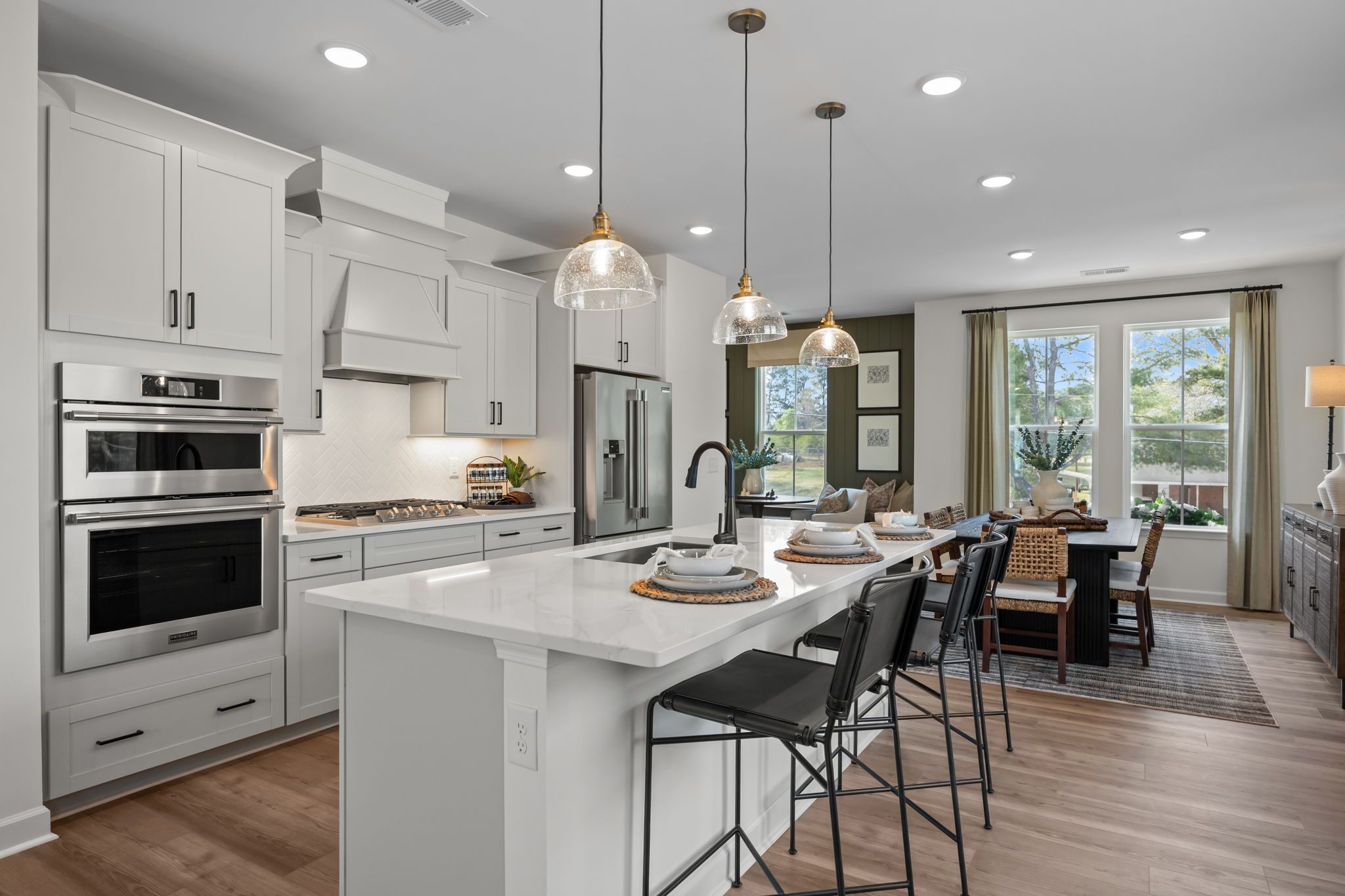 Modern white kitchen in Camden Park, Knightdale NC with shaker cabinets, large island bar, stainless steel appliances, hardwood floors