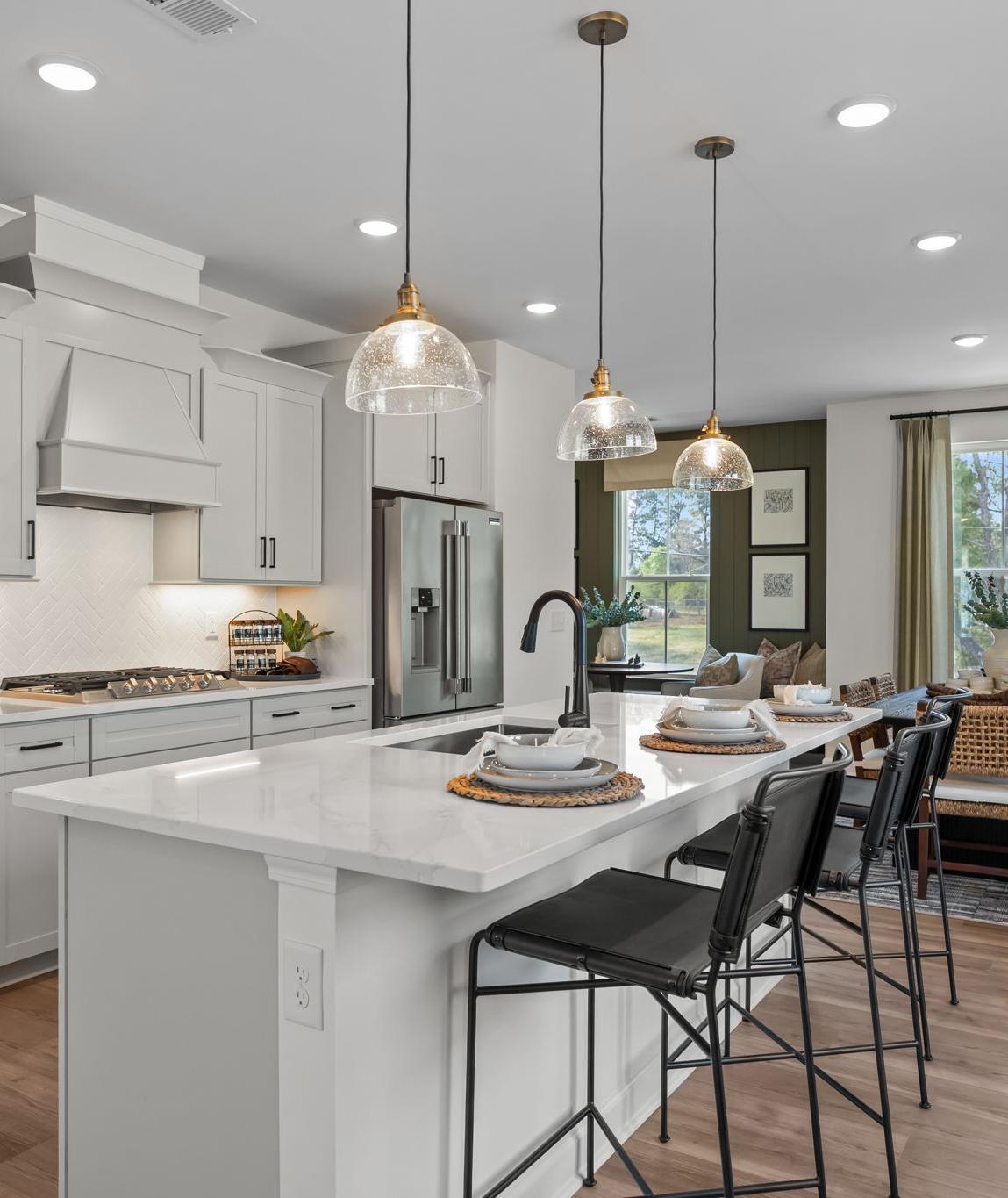 Modern white kitchen in Camden Park, Knightdale NC with shaker cabinets, large island bar, stainless steel appliances, hardwood floors