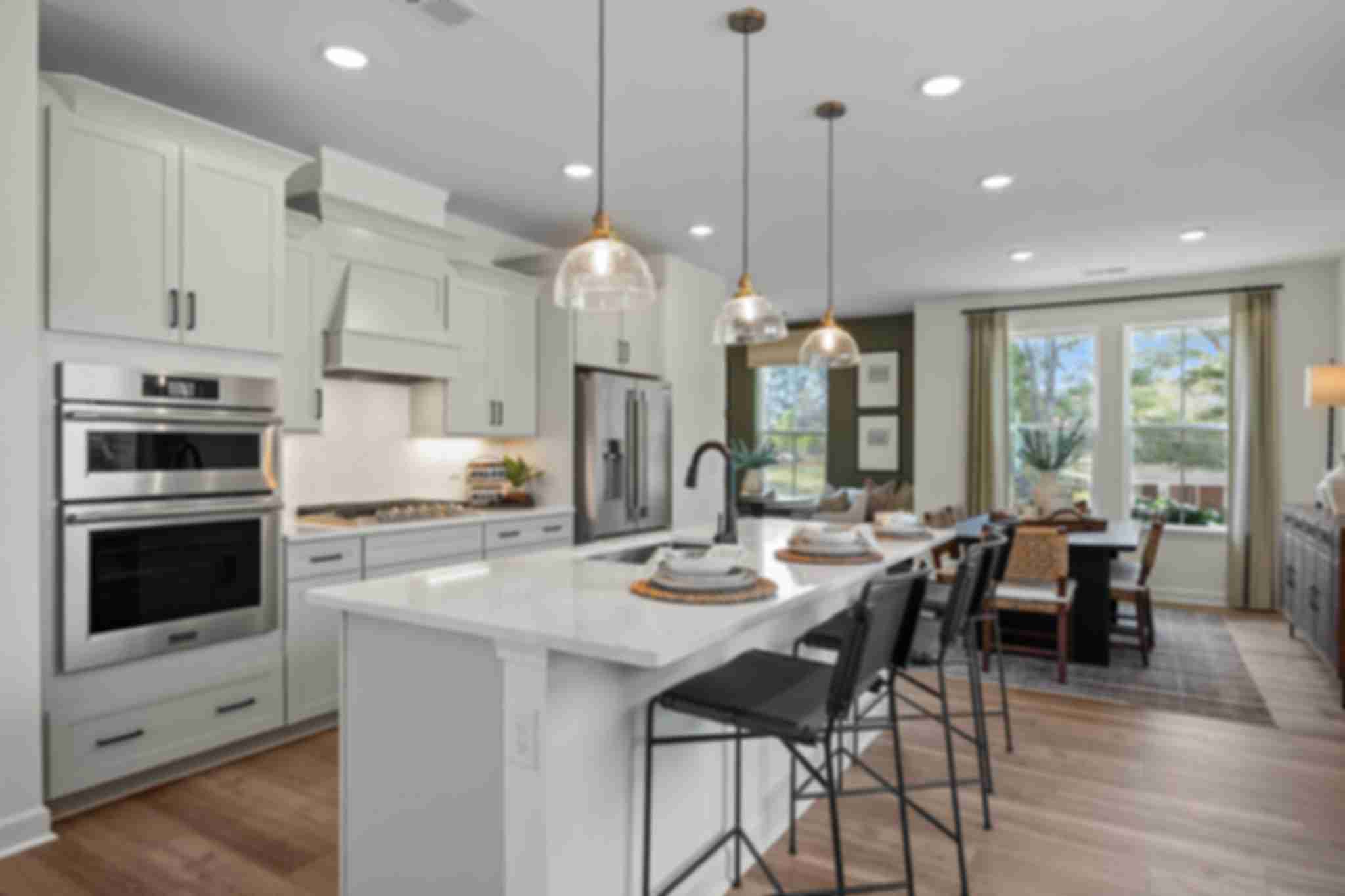 Modern white kitchen in Camden Park, Knightdale NC with shaker cabinets, large island bar, stainless steel appliances, hardwood floors