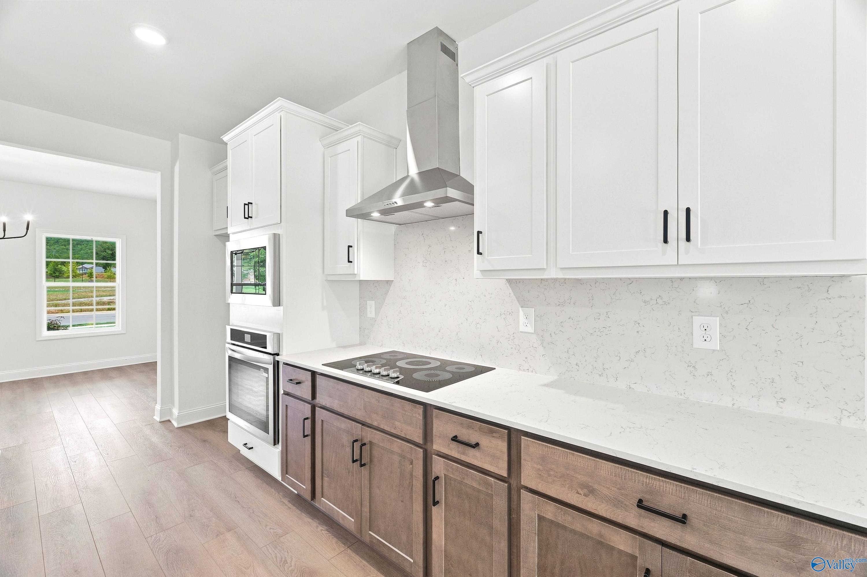 Modern kitchen with two-tone cabinetry, quartz countertops, and stainless steel appliances in The Shelby B, Huntsville home.