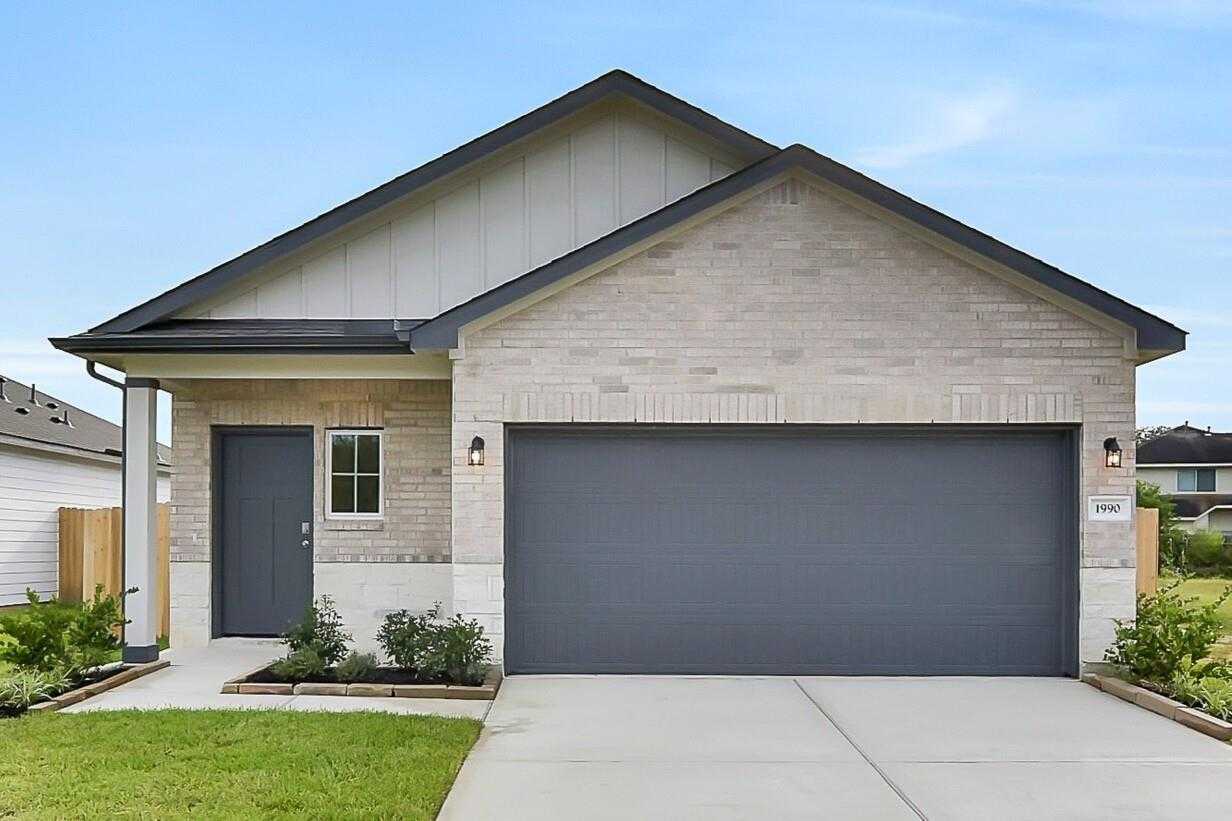 Modern 1-story brick home with 2-car garage, covered porch, and lush landscaping in The Villages at WestPointe, Dayton, Texas