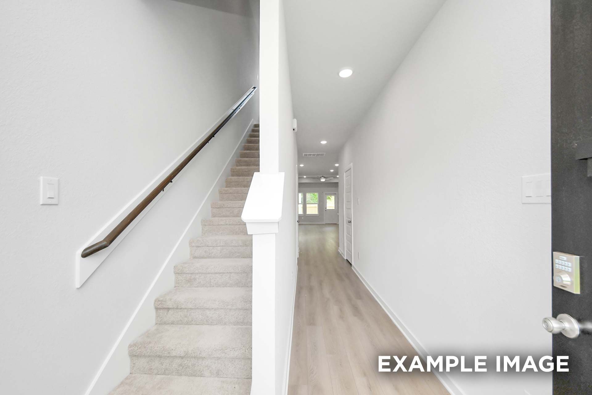 Carpeted staircase and hardwood-floored foyer in The Blanco, a 2-story Davidson Homes new construction home in Beasley, Texas