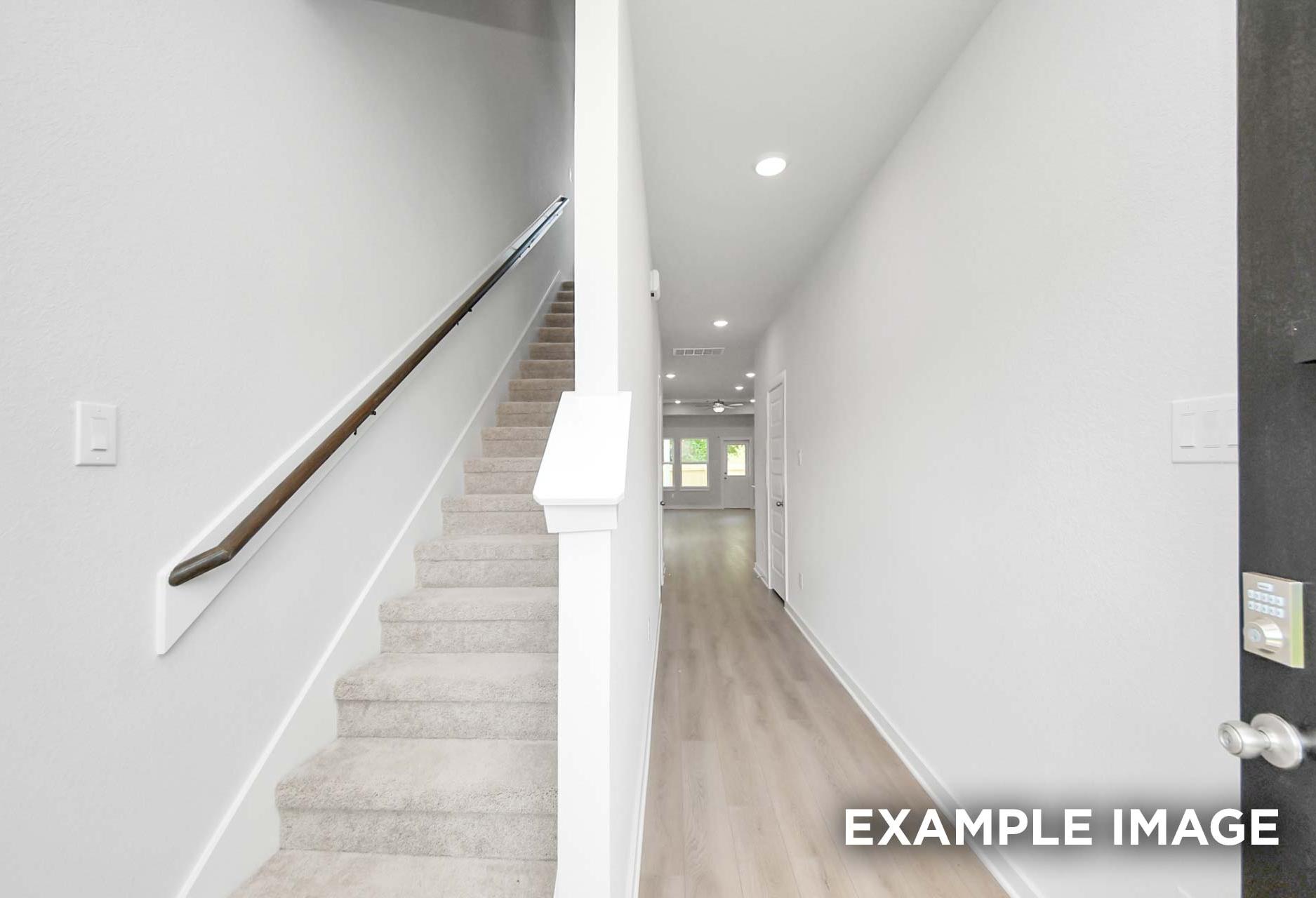 Carpeted staircase and hardwood-floored foyer in The Blanco, a 2-story Davidson Homes new construction home in Beasley, Texas