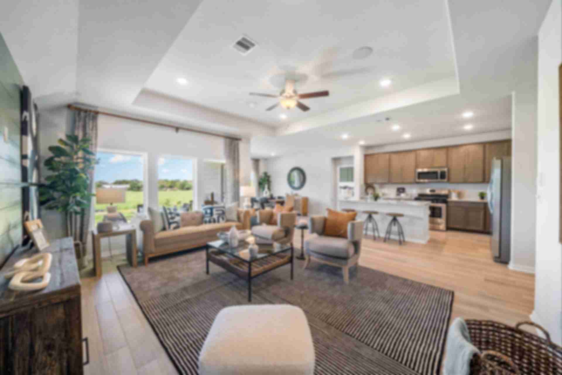 Open-concept living room and kitchen at Windmill Estates in Magnolia Texas with hardwood floors, large windows, and modern decor