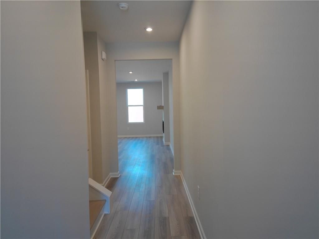 Bright hallway with light hardwood floors, neutral walls, staircase, and sunlit window in Davidson Homes The Marion C, Winder, Georgia